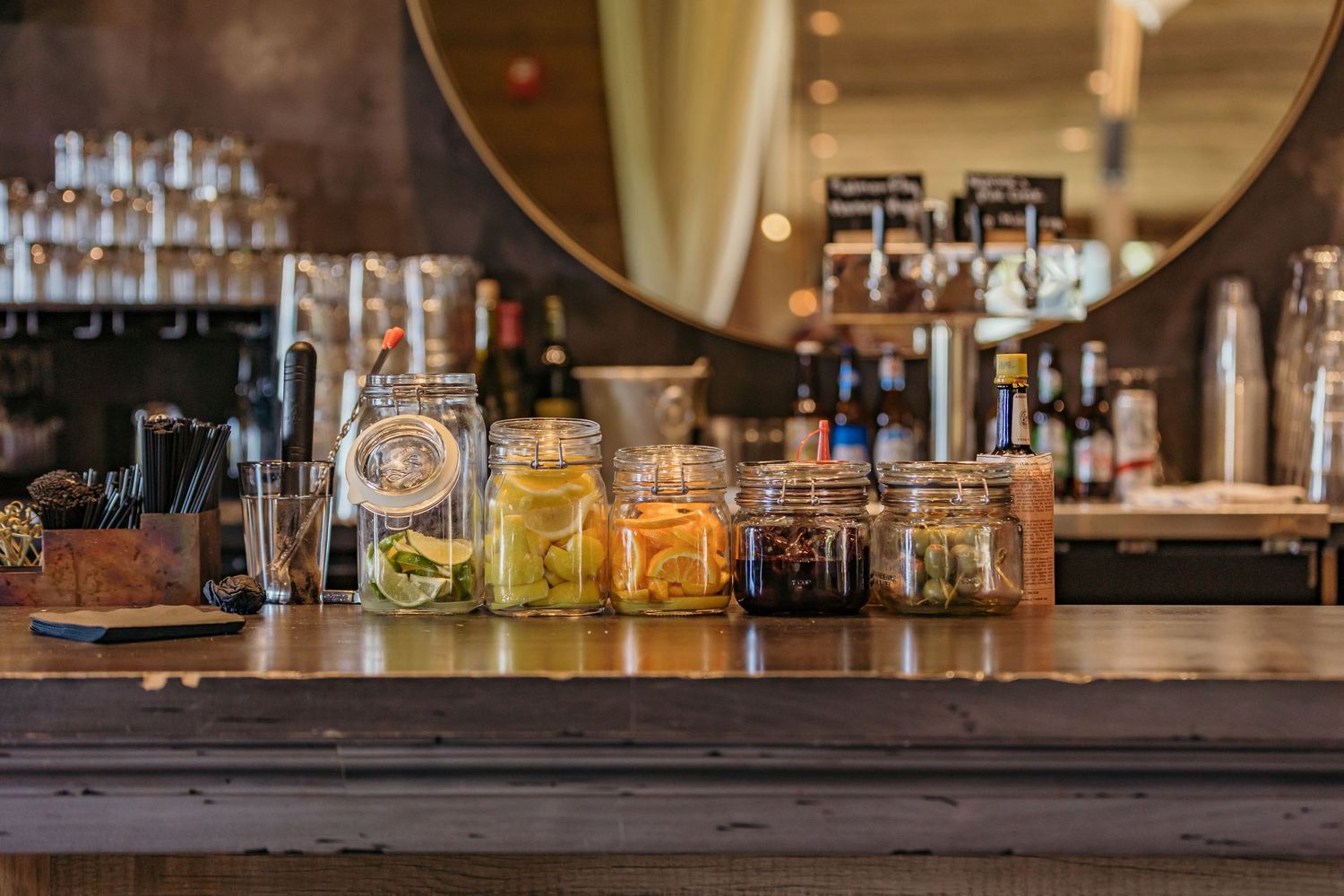 Bar setup with various liquor bottles and glasses displayed on a dark wooden counter.