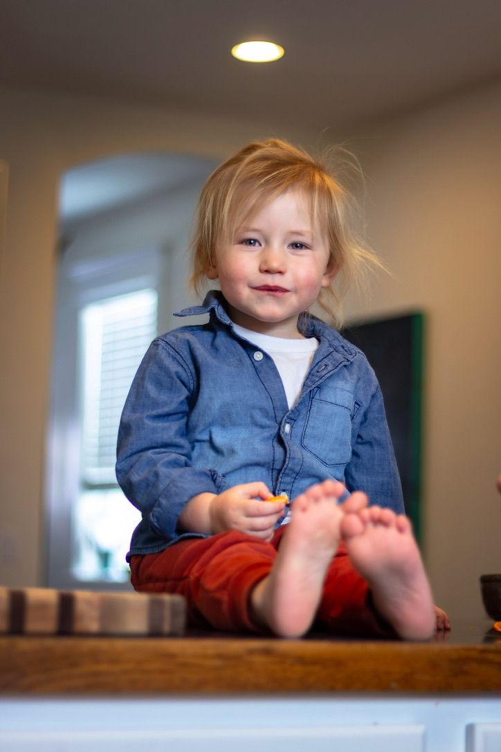 Close-up view of bare feet and denim clothing on a wooden surface in natural lighting.