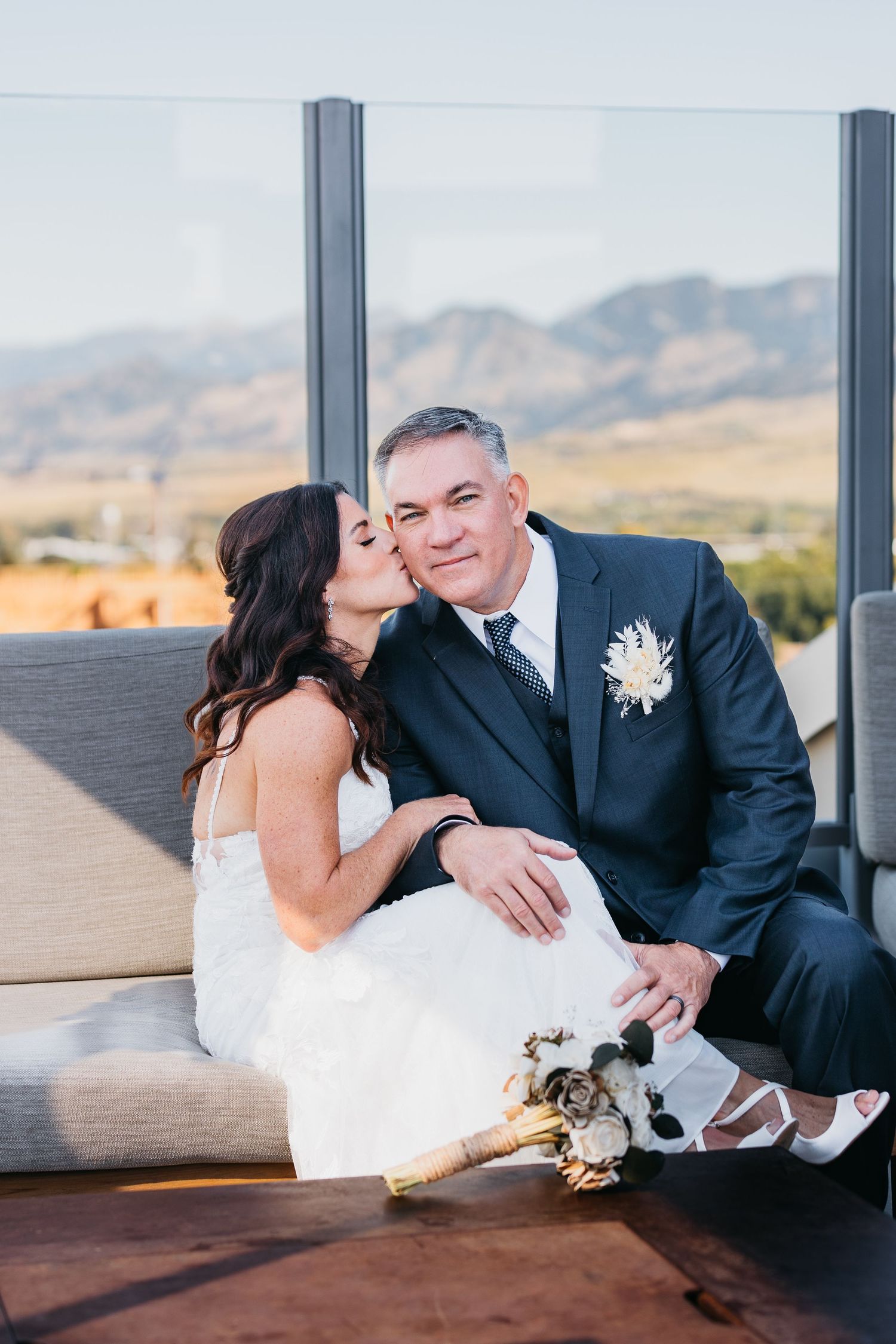 Couple relaxing on outdoor lounge furniture with mountain views in background.