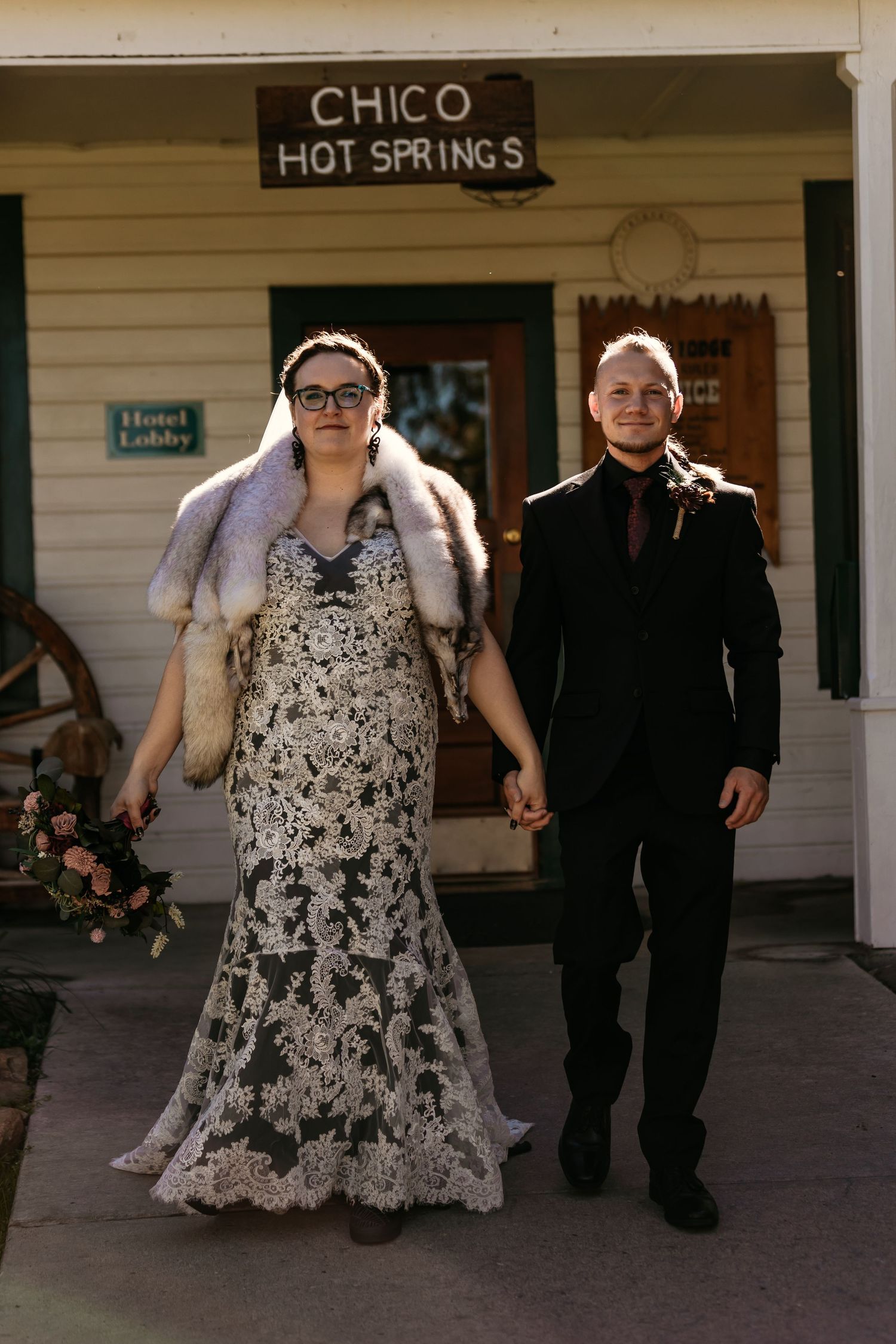 Wedding couple walking past Chico Hot Springs sign in formal attire.