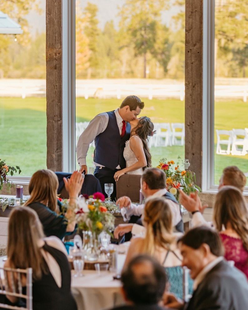 A reception moment during toasts with guests seated at decorated tables.
