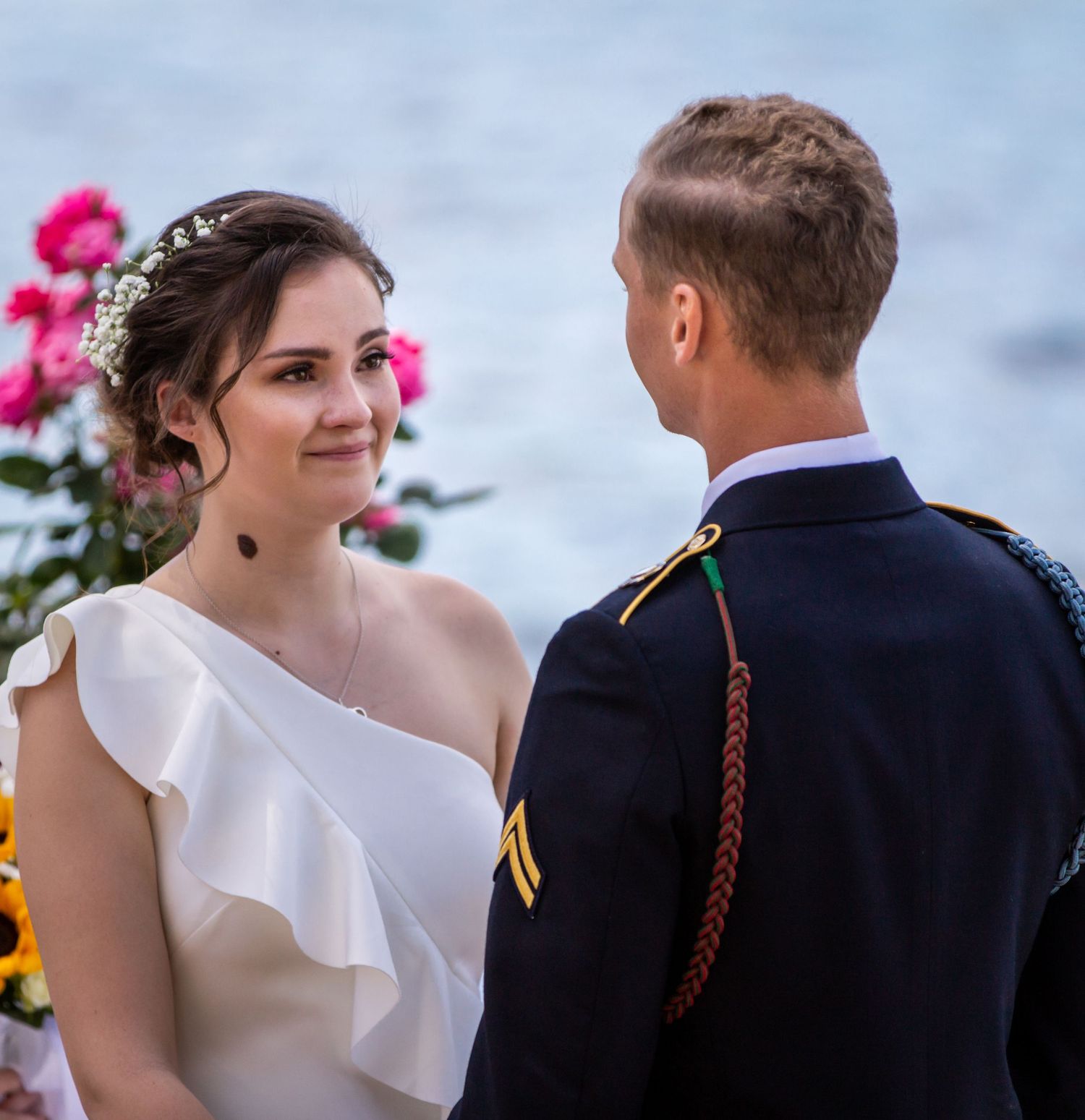 An outdoor wedding ceremony features bright pink flowers and formal attire.