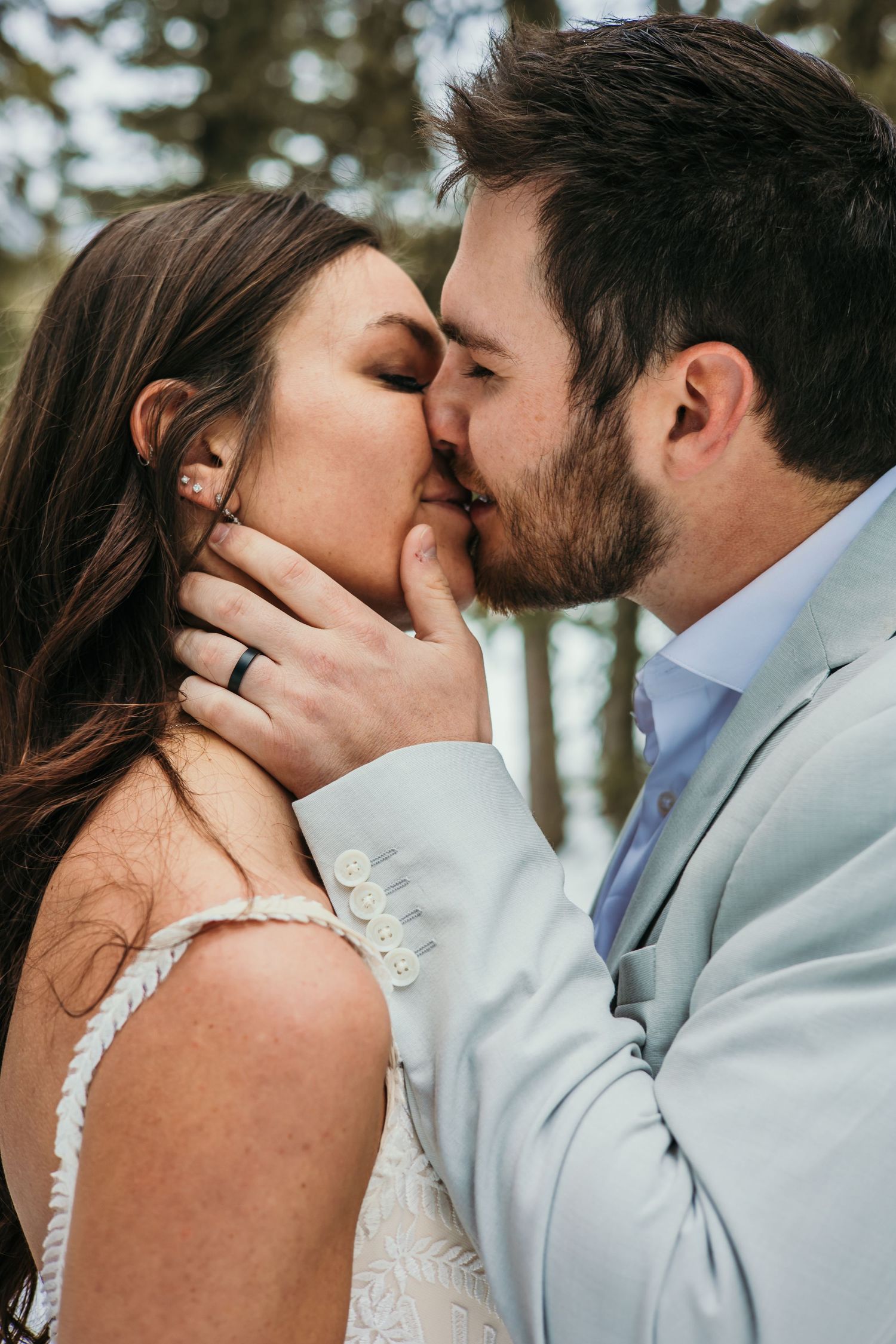 A romantic winter wedding kiss against a snowy mountain backdrop.