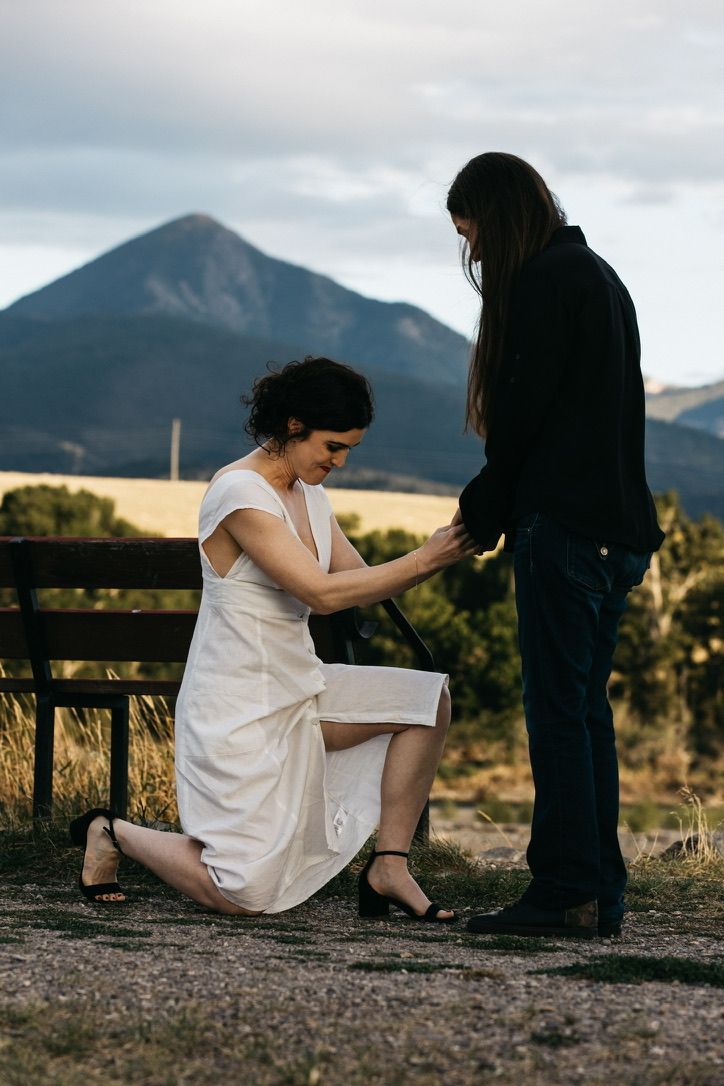 Romantic mountain proposal scene with scenic mountain peak in background.