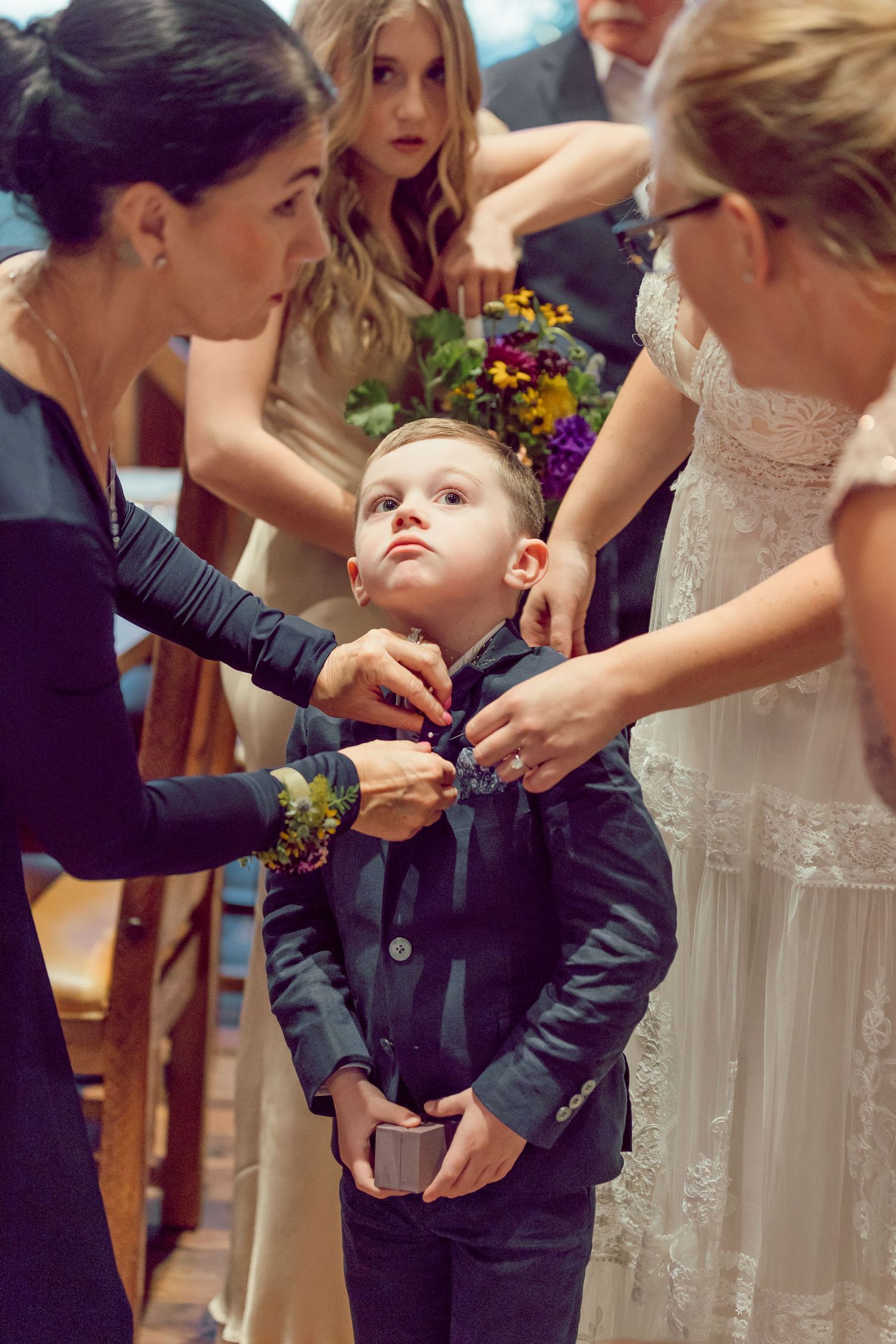 Wedding party helping adjust formal attire and accessories before ceremony.