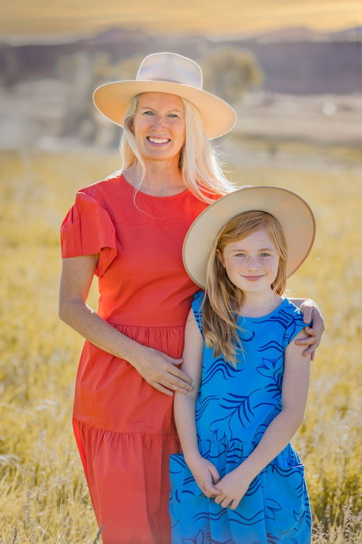 Bright summer field scene with red and blue dresses against golden grass.