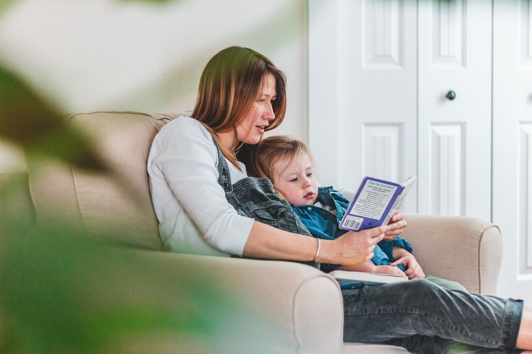 A cozy scene of reading together on a white couch with a tablet device.