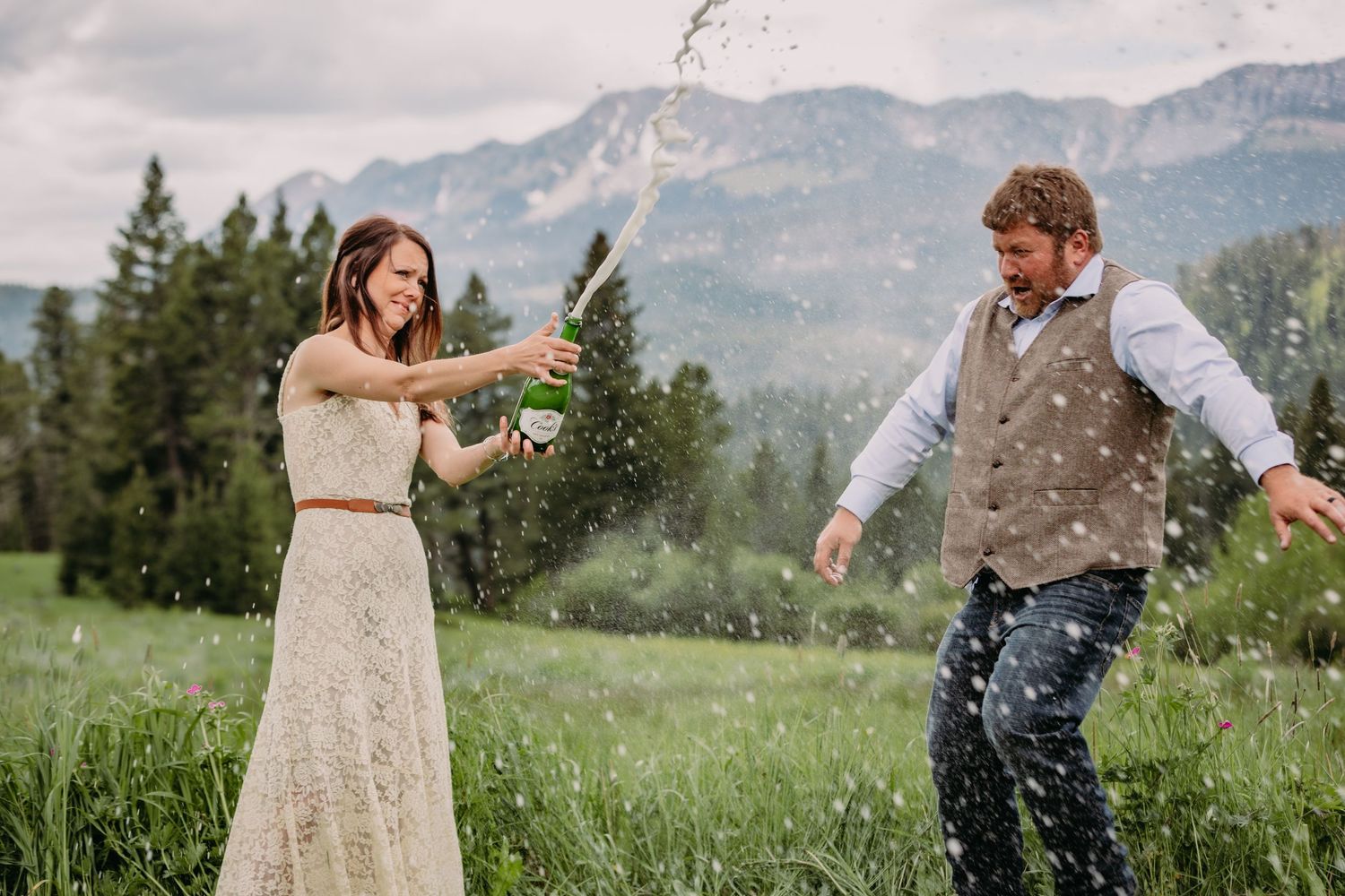 Playful wedding photo sequence in a mountain meadow with natural scenery.