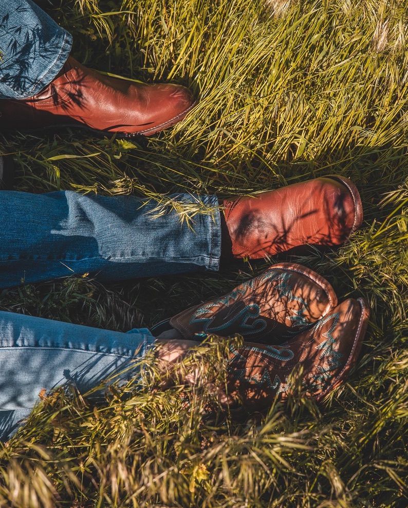 Couple lying in golden grass during sunset photoshoot with natural lighting.