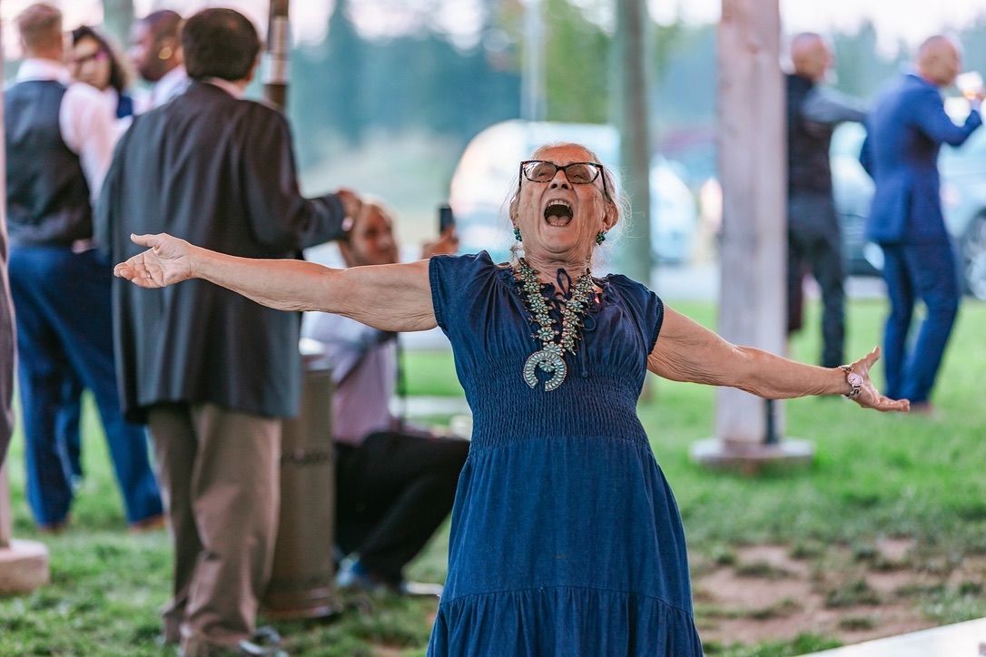 Wedding party celebrating outdoors with joyful expressions and dancing.
