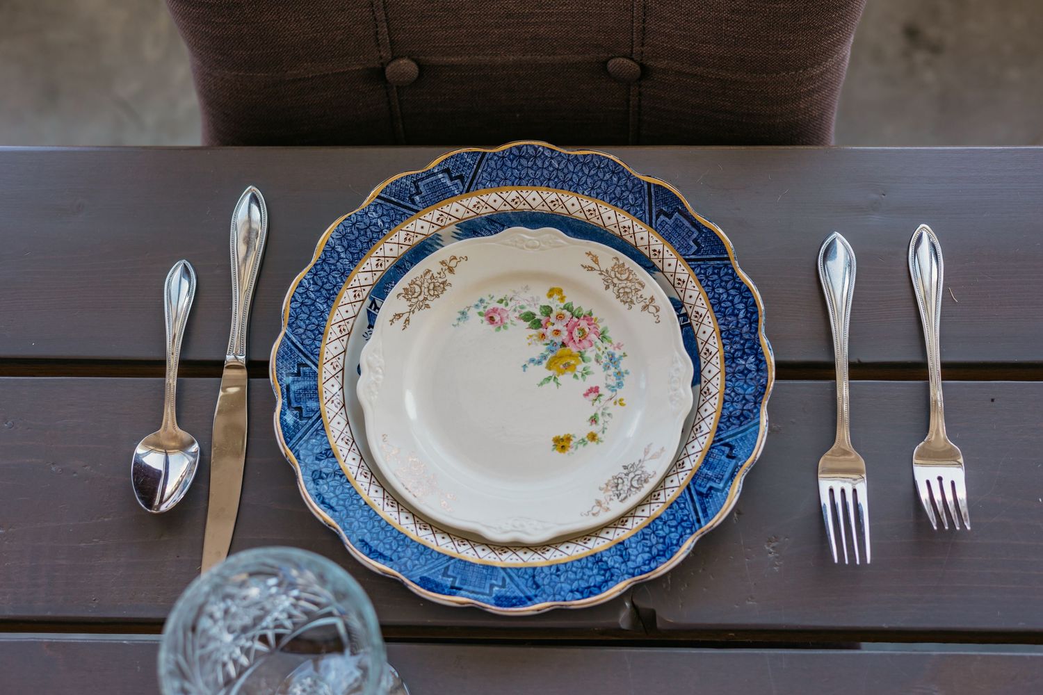Formal place settings with blue-rimmed plates and silver cutlery arranged on dark wooden tables.