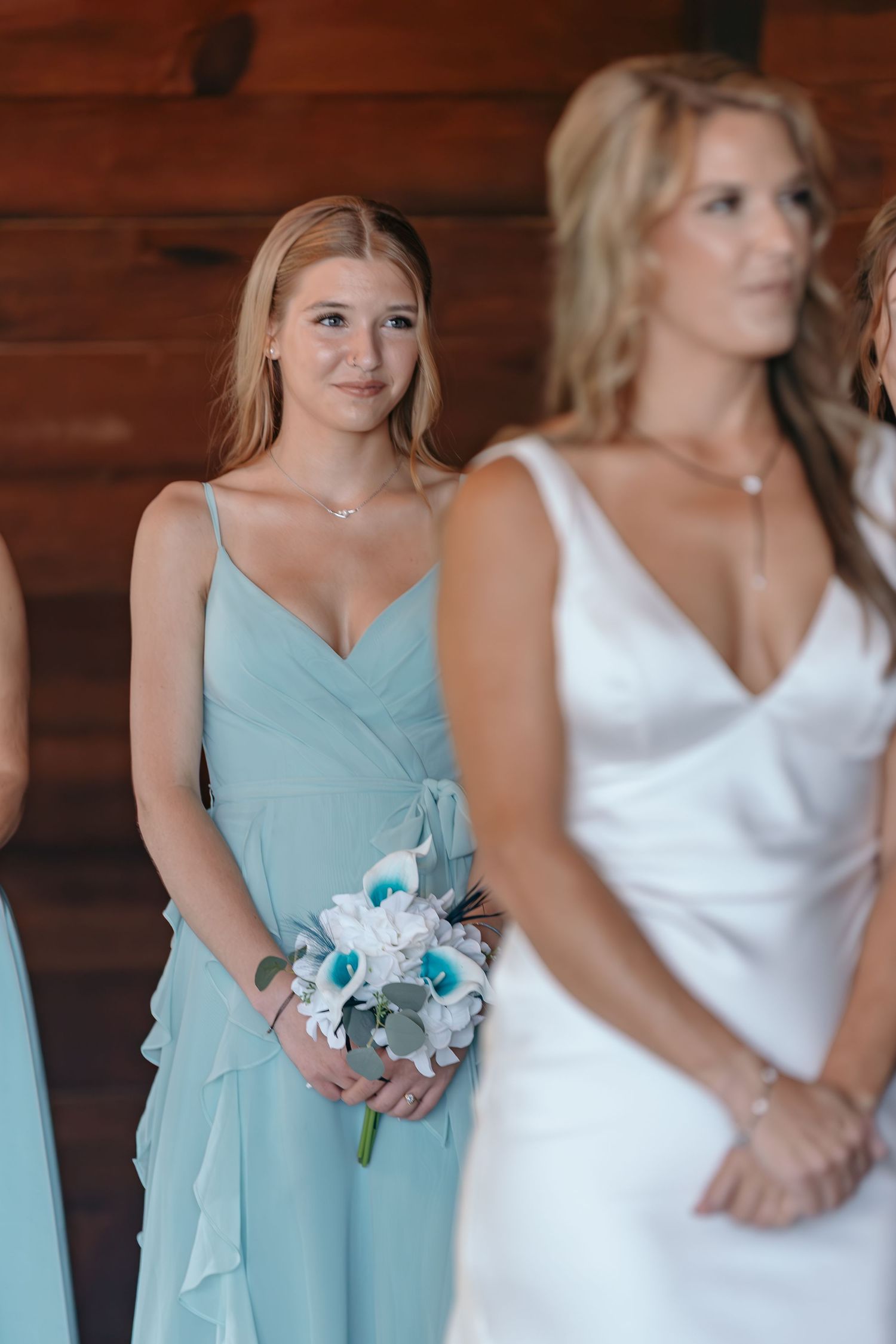 Wedding party members in light blue dresses and white gown standing together indoors.