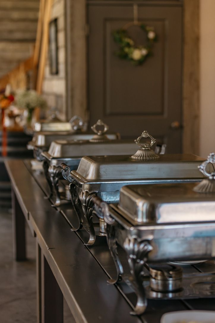 Row of silver chafing dishes set up for wedding catering service.