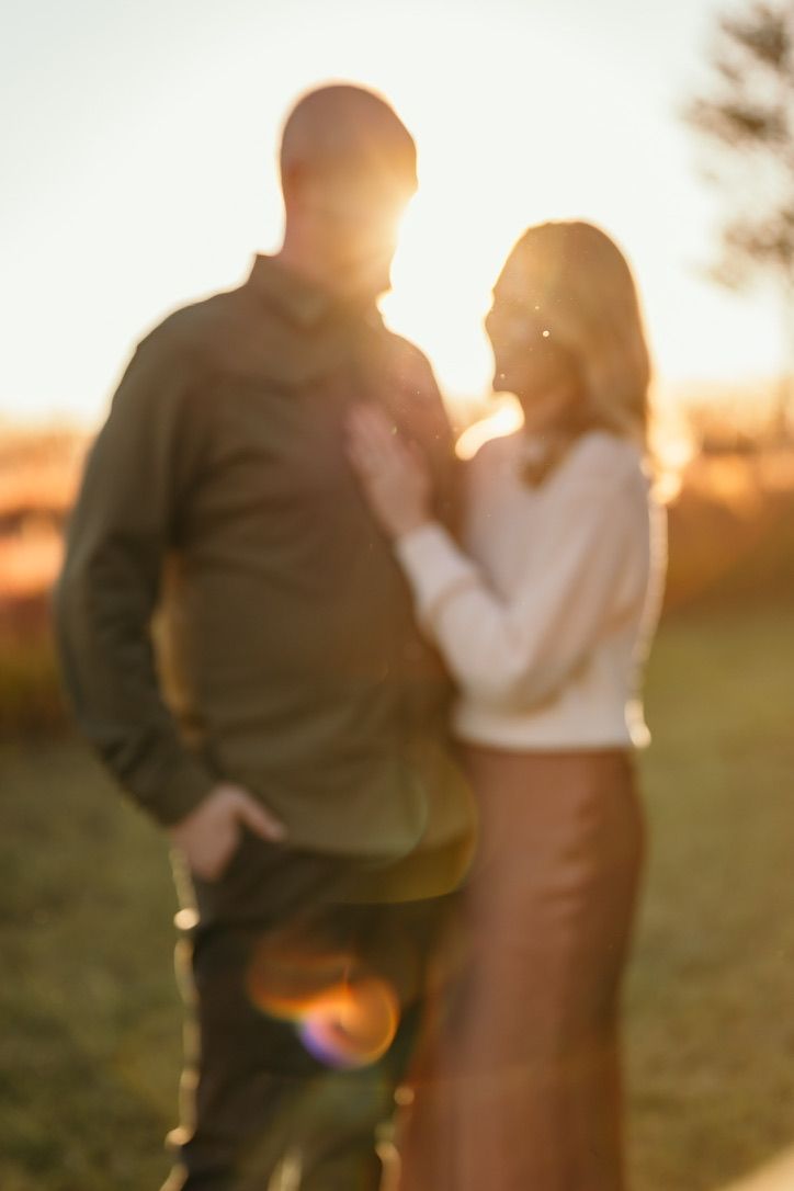 Silhouette of couple standing together at sunset in a field.