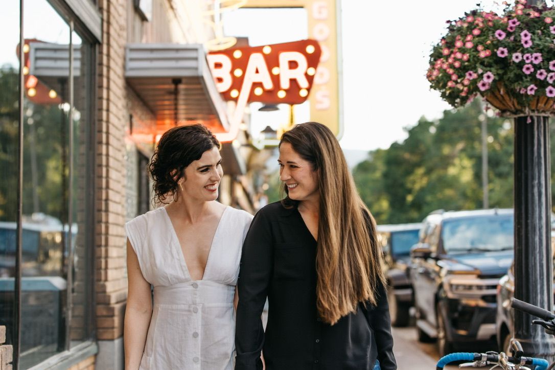 A couple shares romantic moments outside a downtown storefront with string lights and flowers.