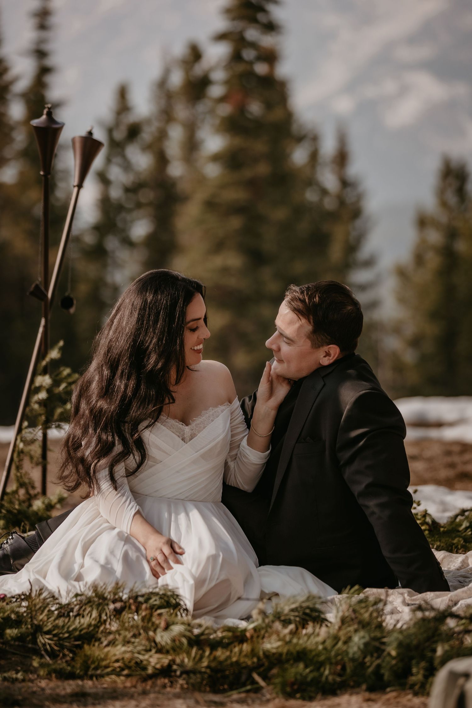 Intimate wedding couple moment captured in snowy mountain setting.