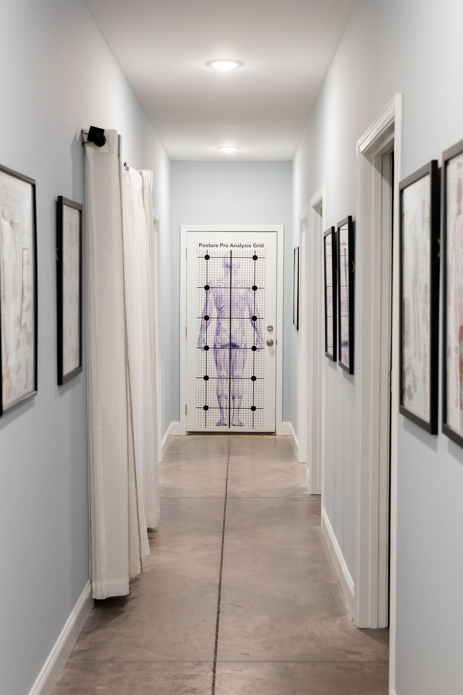 Long white hallway with modern black framed artwork displayed along the walls and recessed lighting overhead.