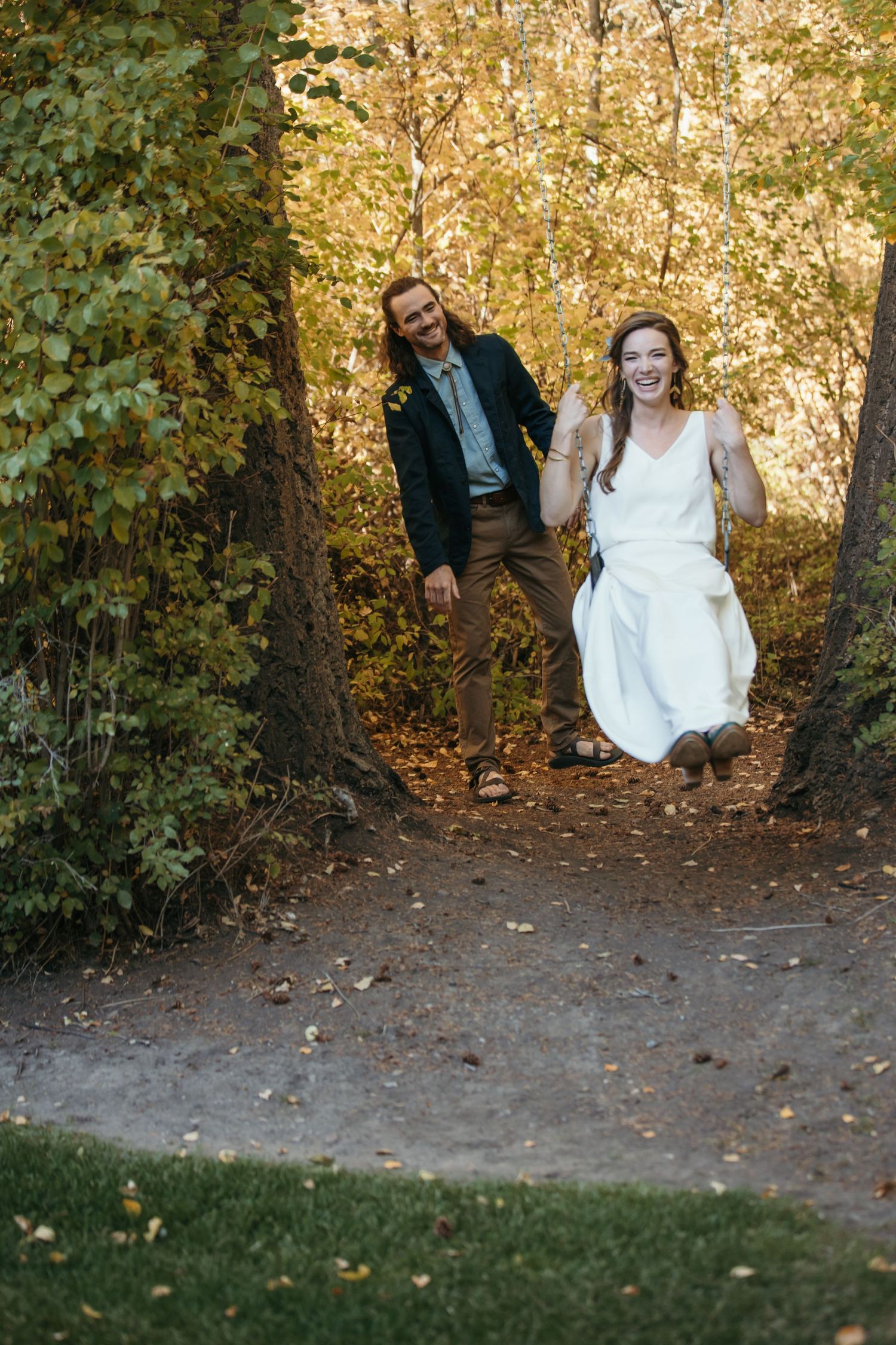 Playful sequence of couple emerging from wooded path in wedding attire.