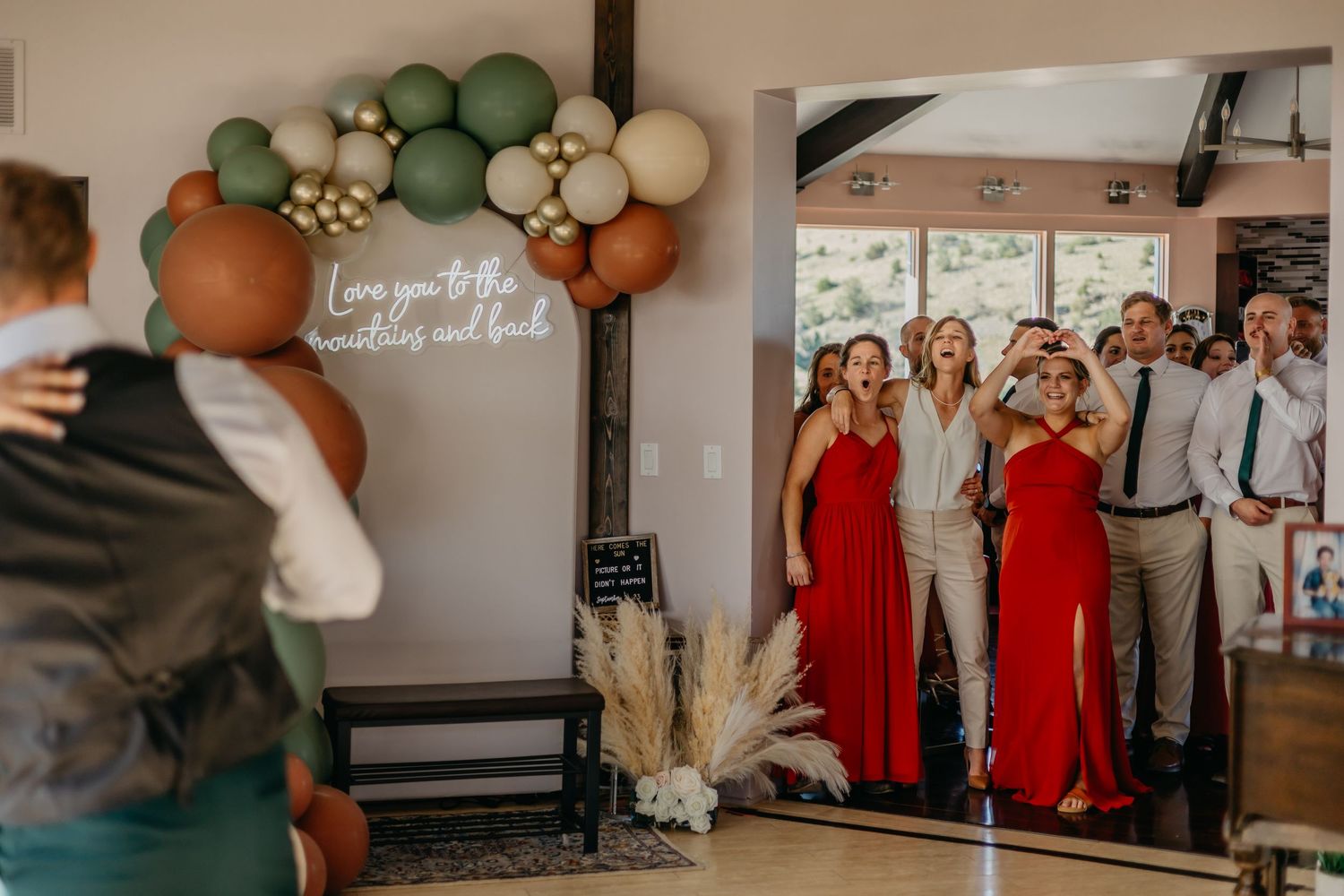 Wedding reception venue decorated with green and white balloon garlands and red accents.