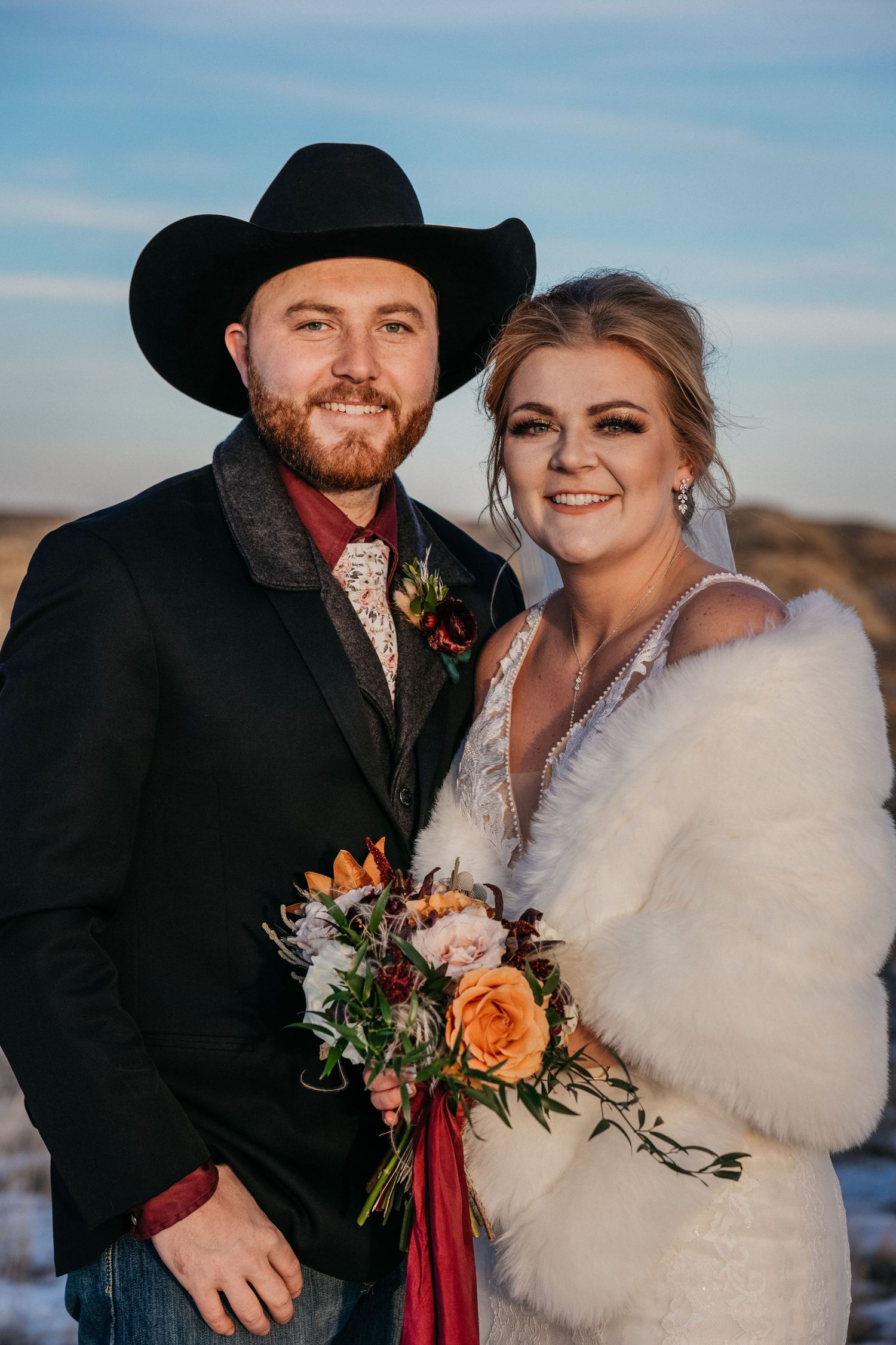 Winter wedding portraits featuring western style with cowboy hat and fur wrap.