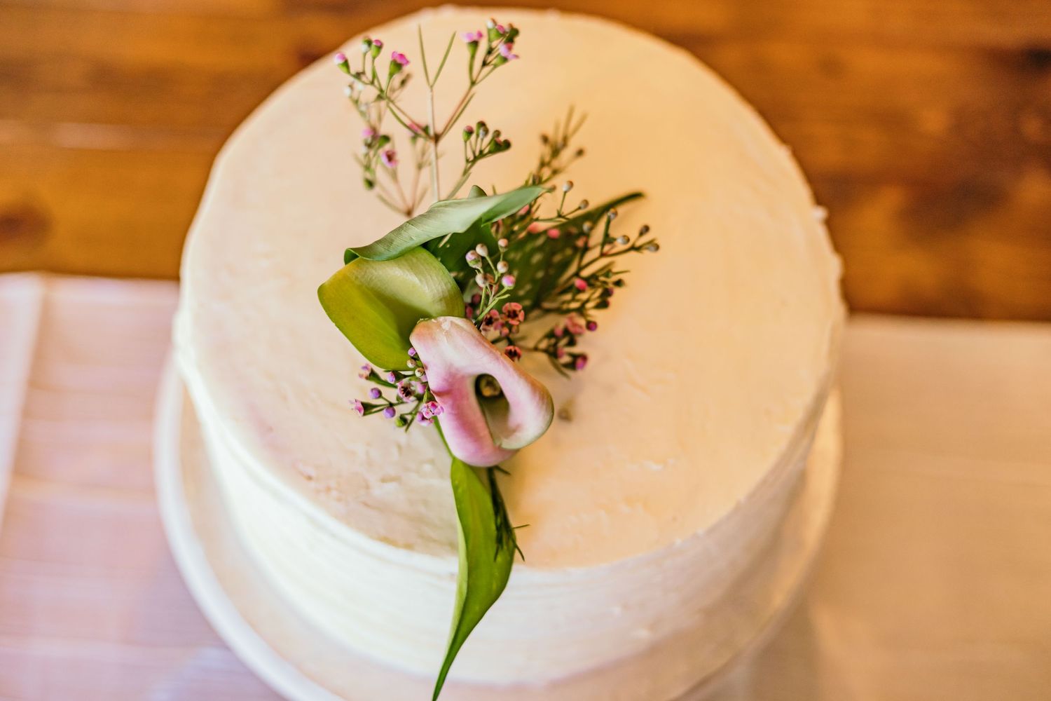 White wedding cake decorated with delicate floral accents and greenery.