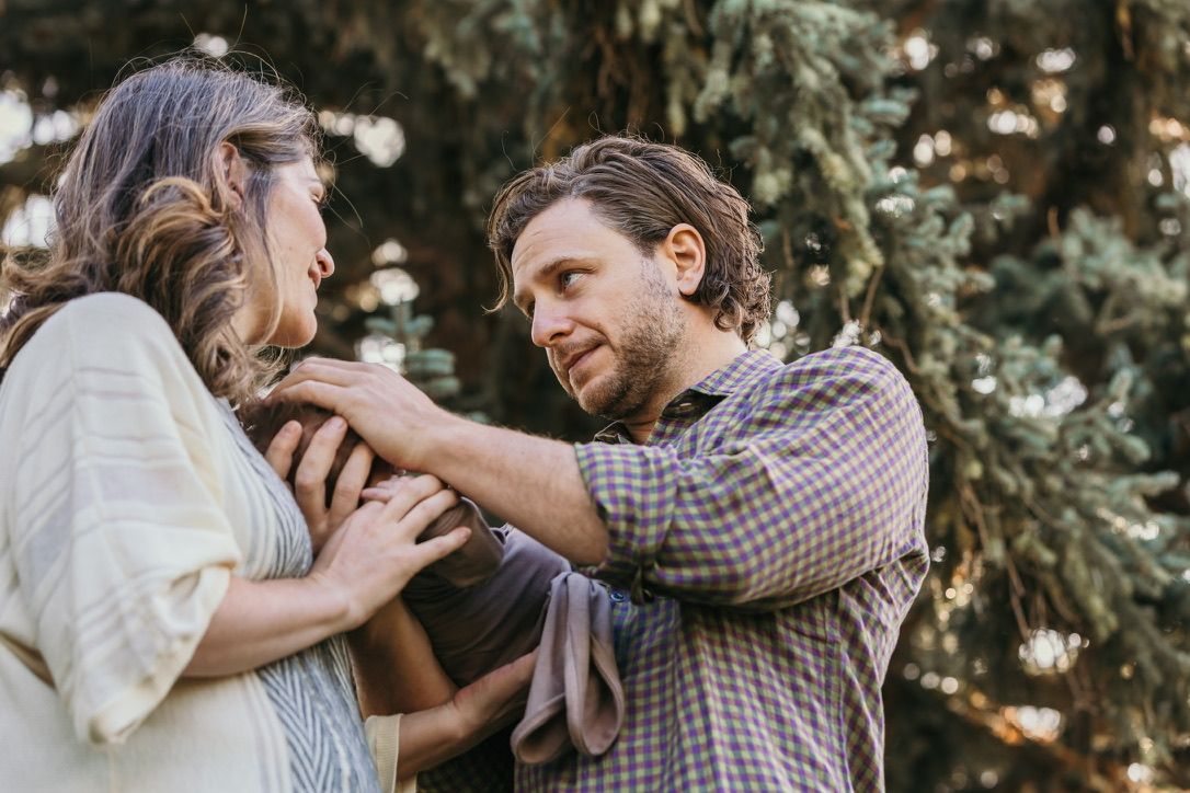A tender moment between a couple captured in soft lighting among evergreen trees.
