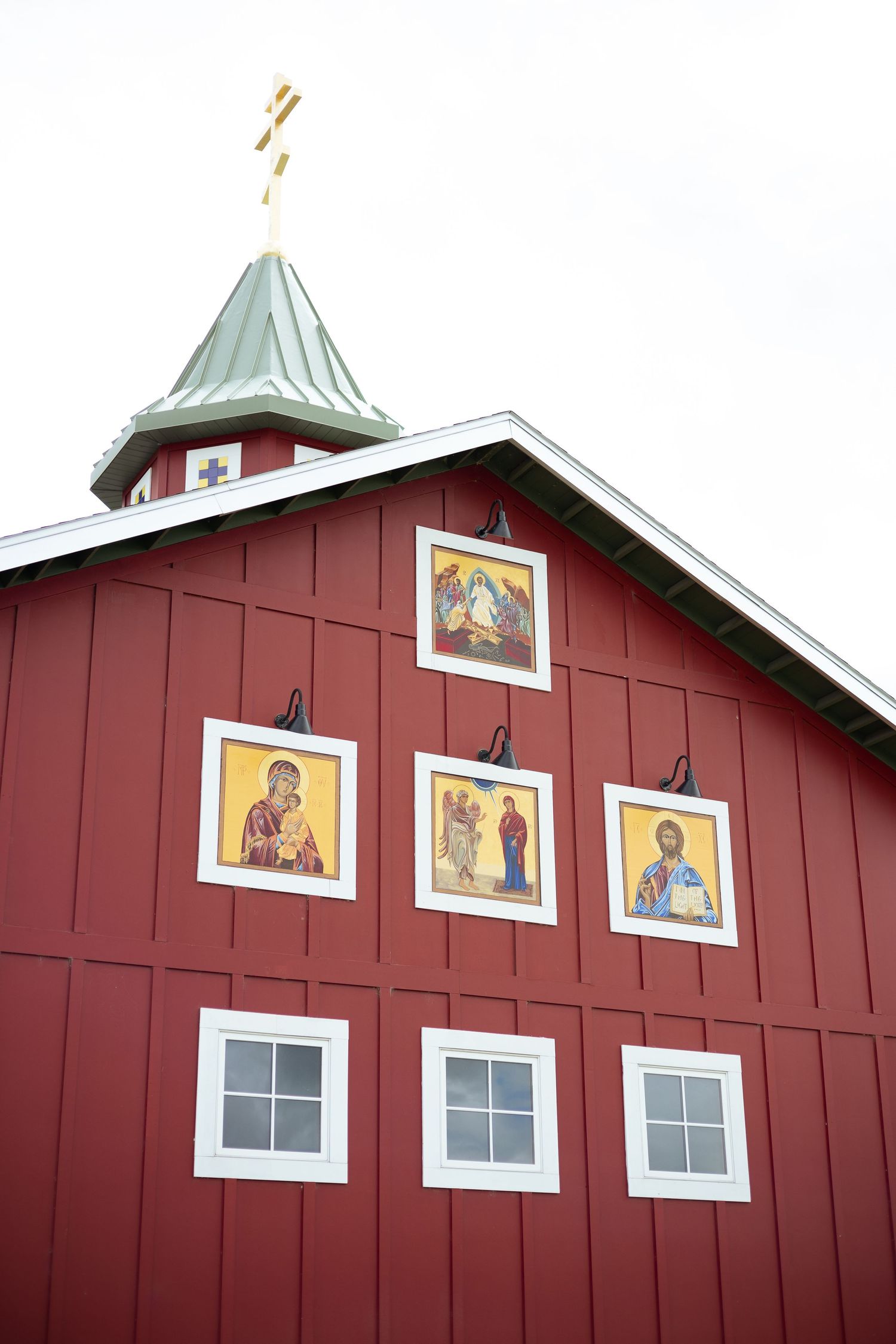 Red barn-style church exterior with decorative religious artwork panels.