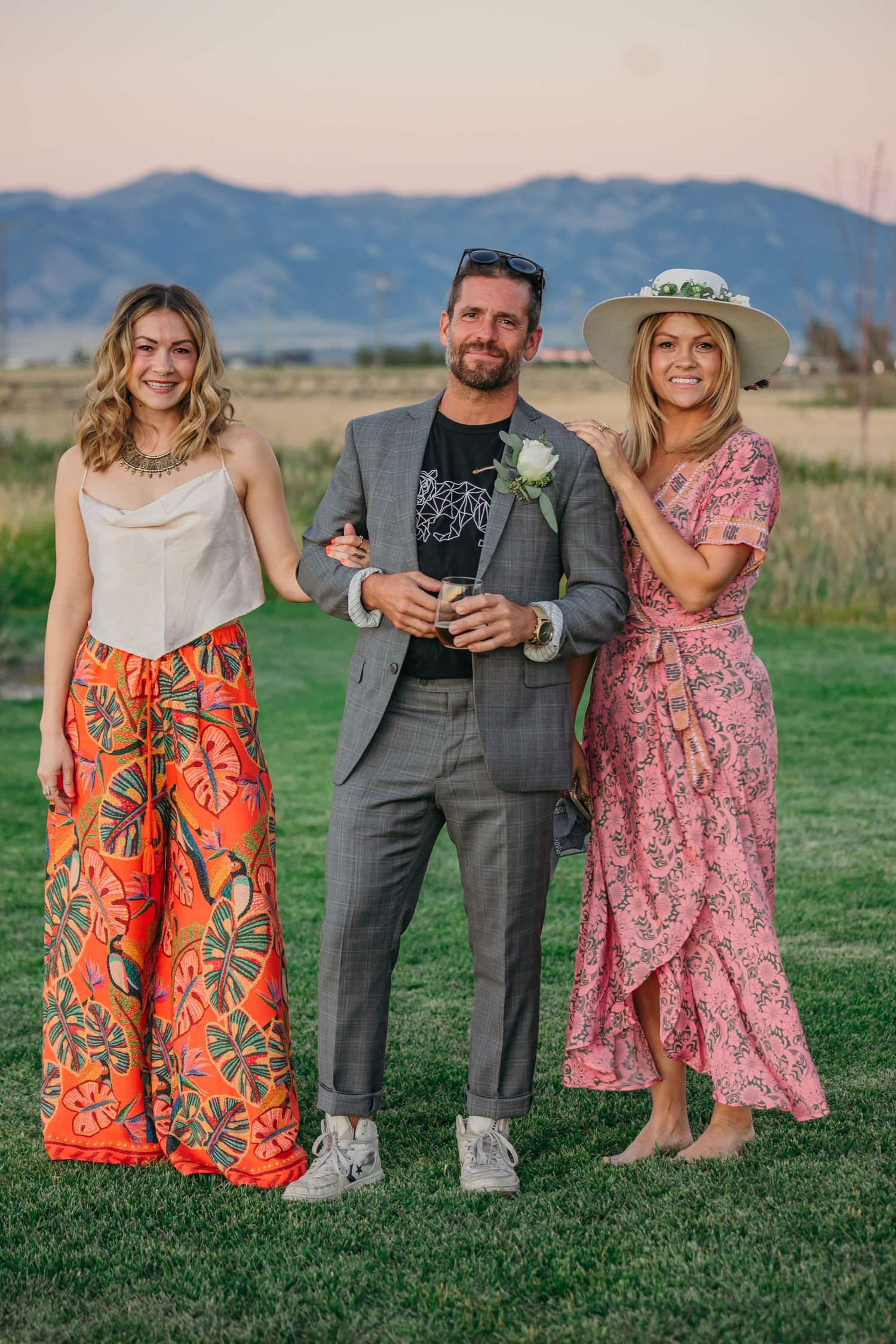 Wedding party members in colorful dresses and formal attire posing against mountain scenery.