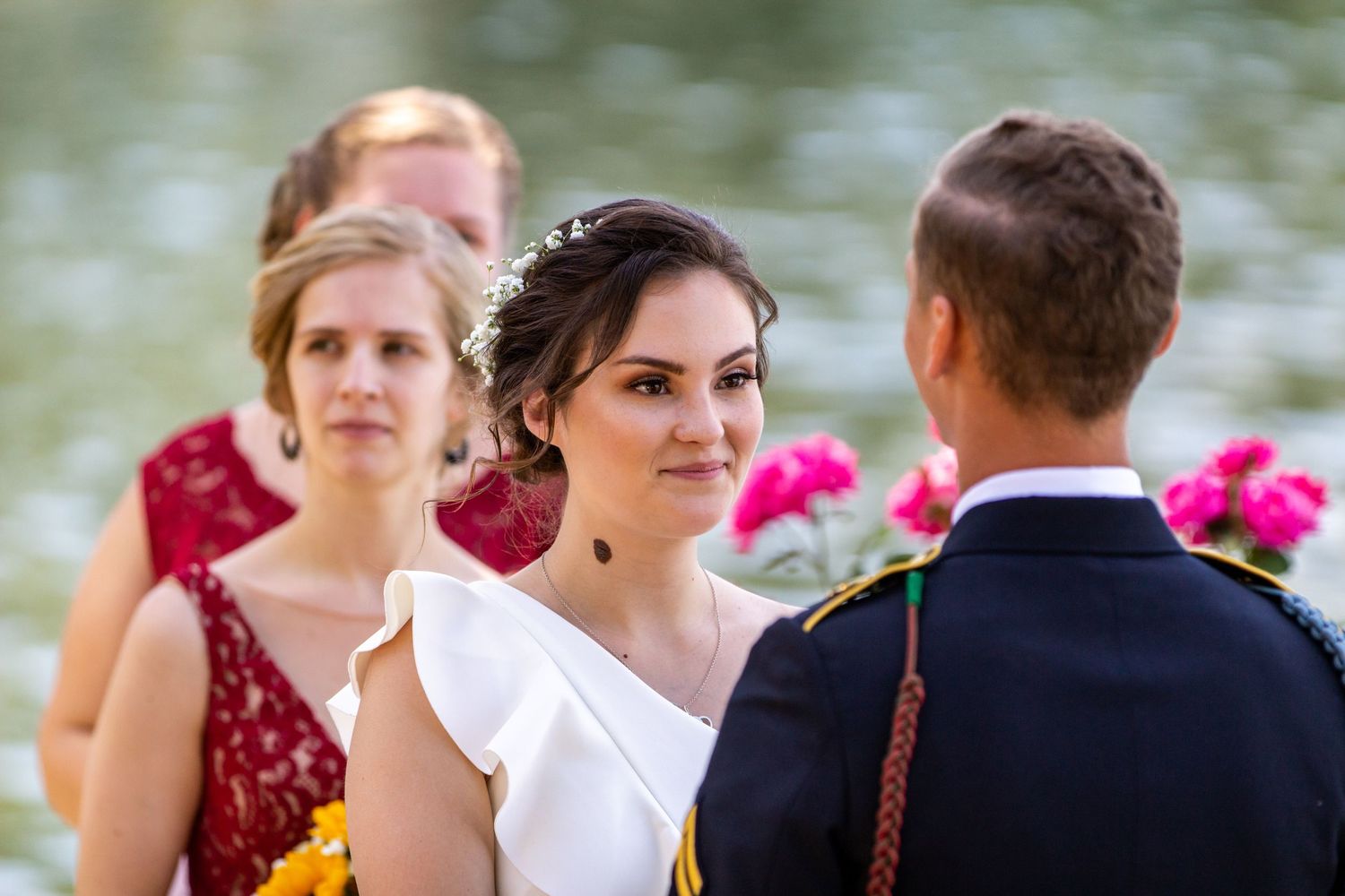 Wedding ceremony guests seated outdoors with pink flowers in foreground.