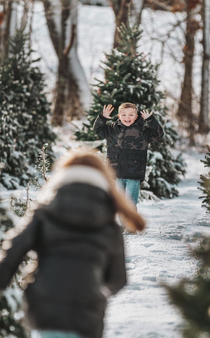 Playing in a snowy forest among evergreen trees during winter.