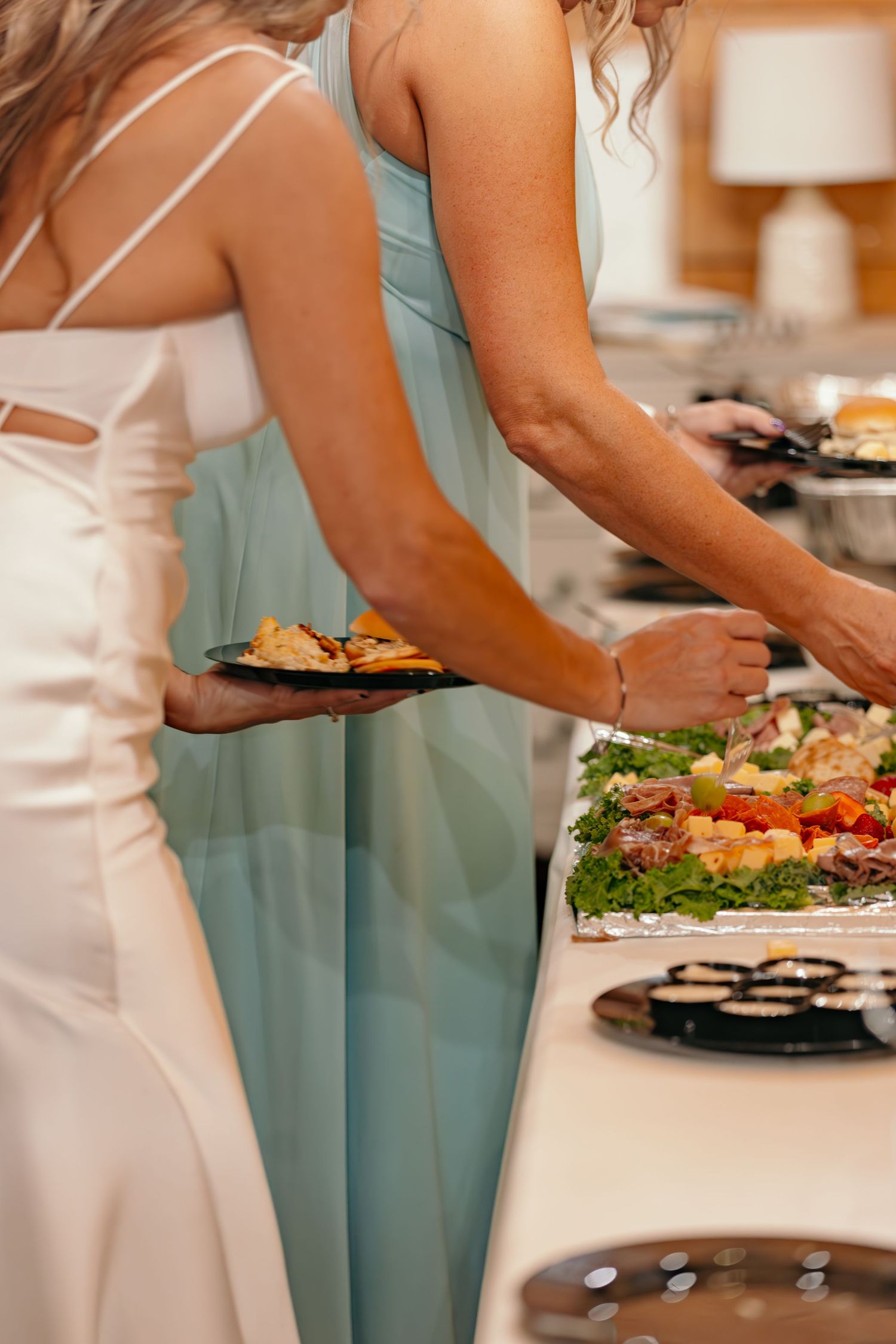 Wedding buffet table with elegant food displays and guests in formal attire serving themselves.