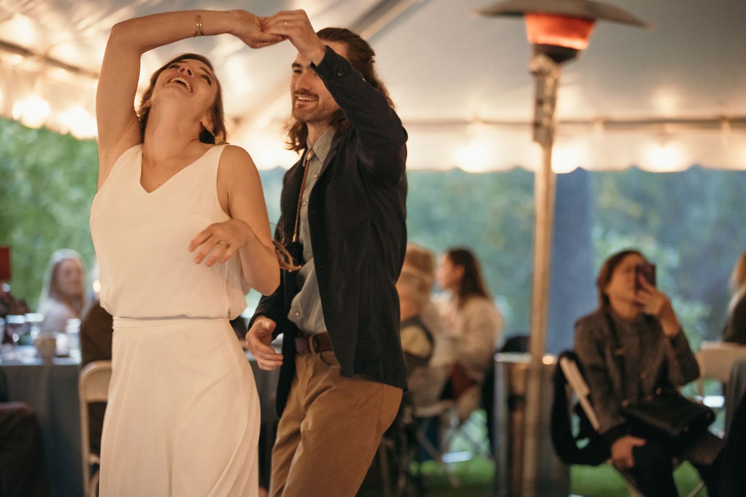 Wedding reception celebration under tent with warm lighting.
