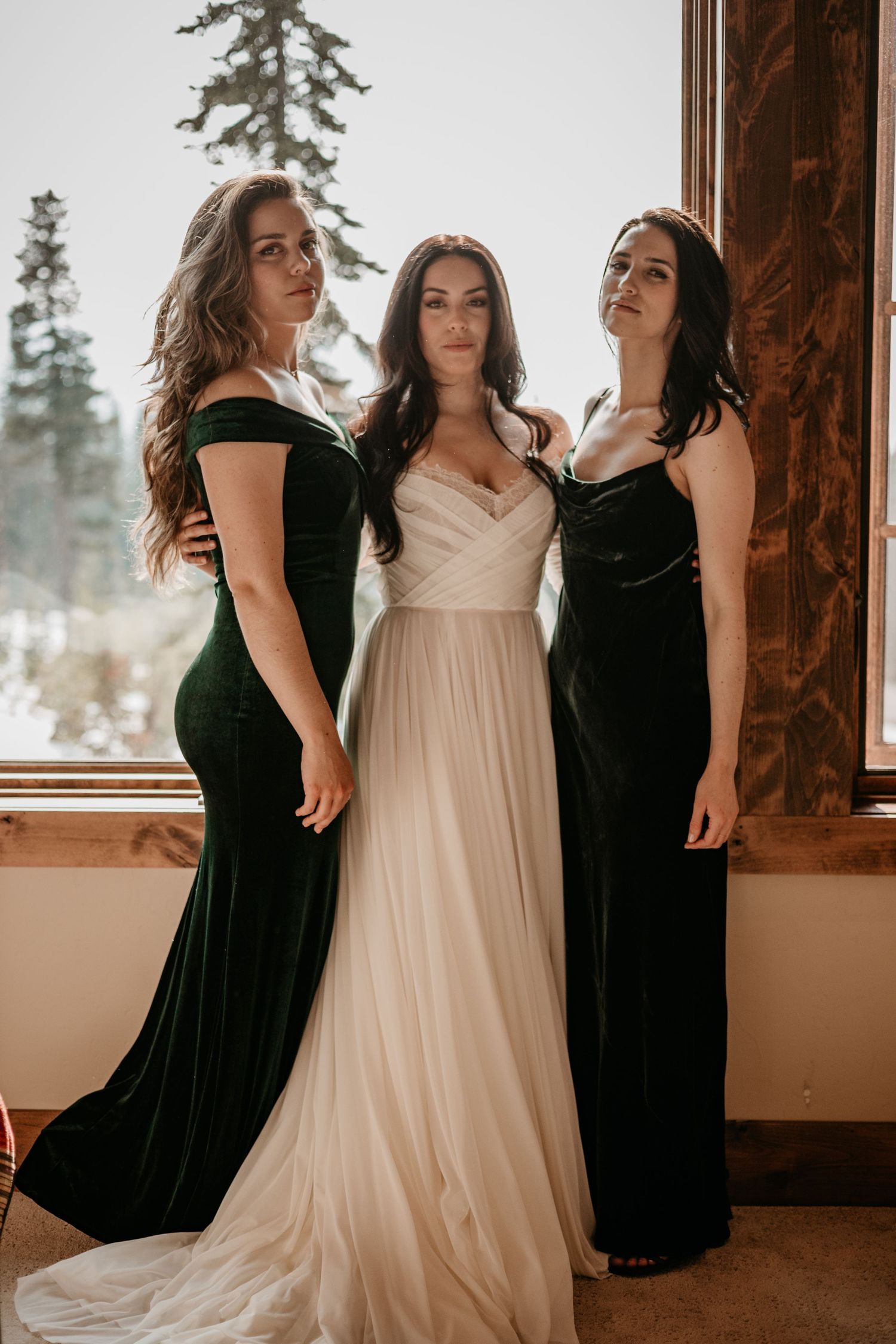 Three people pose together in formal attire with one wearing a flowing white dress.