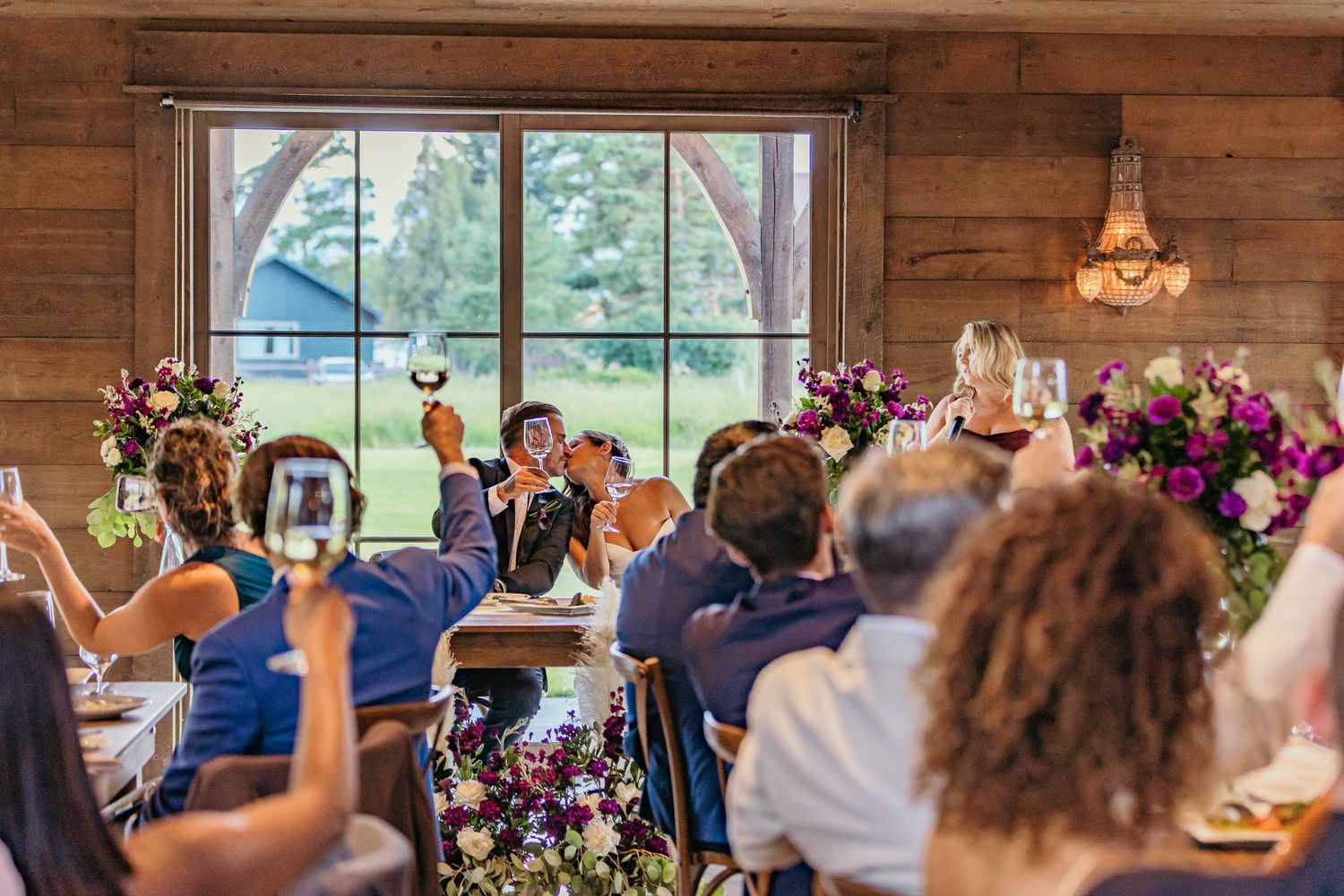 Rustic wedding reception venue decorated with colorful floral arrangements and wooden details.