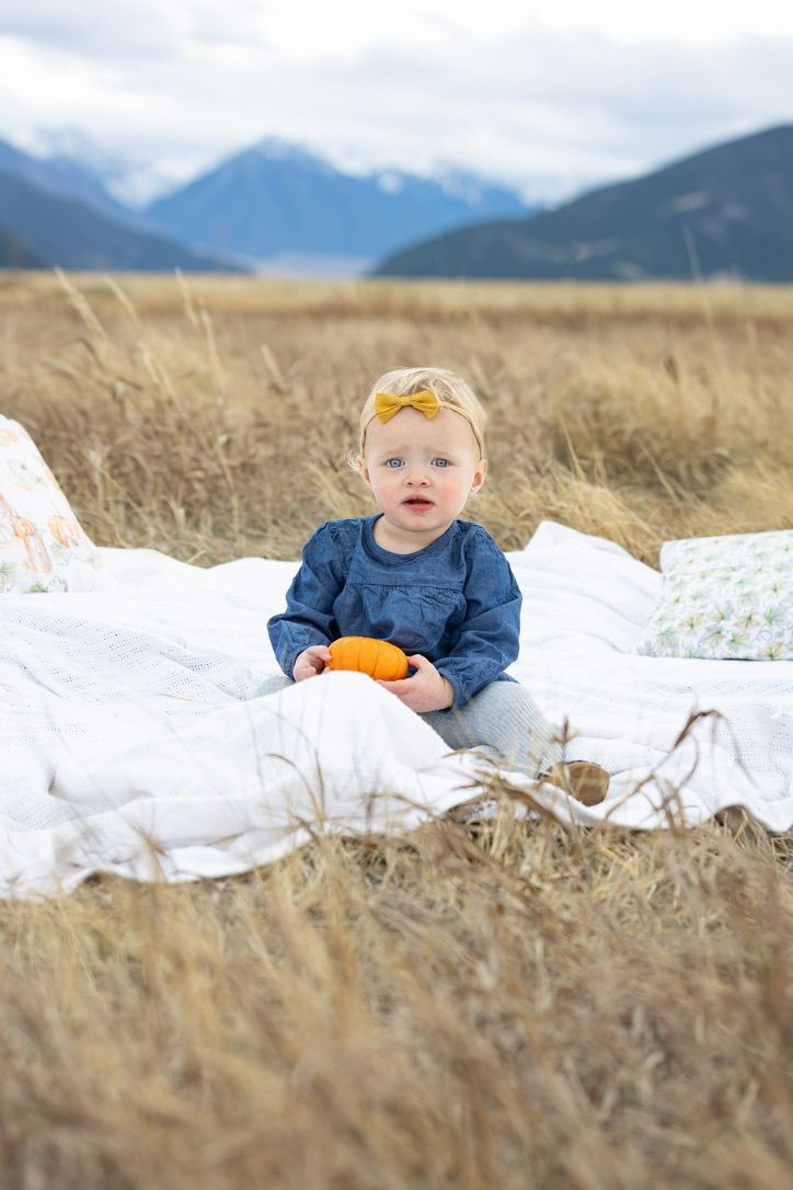 White blanket laid out in grassy field with mountains visible in background.