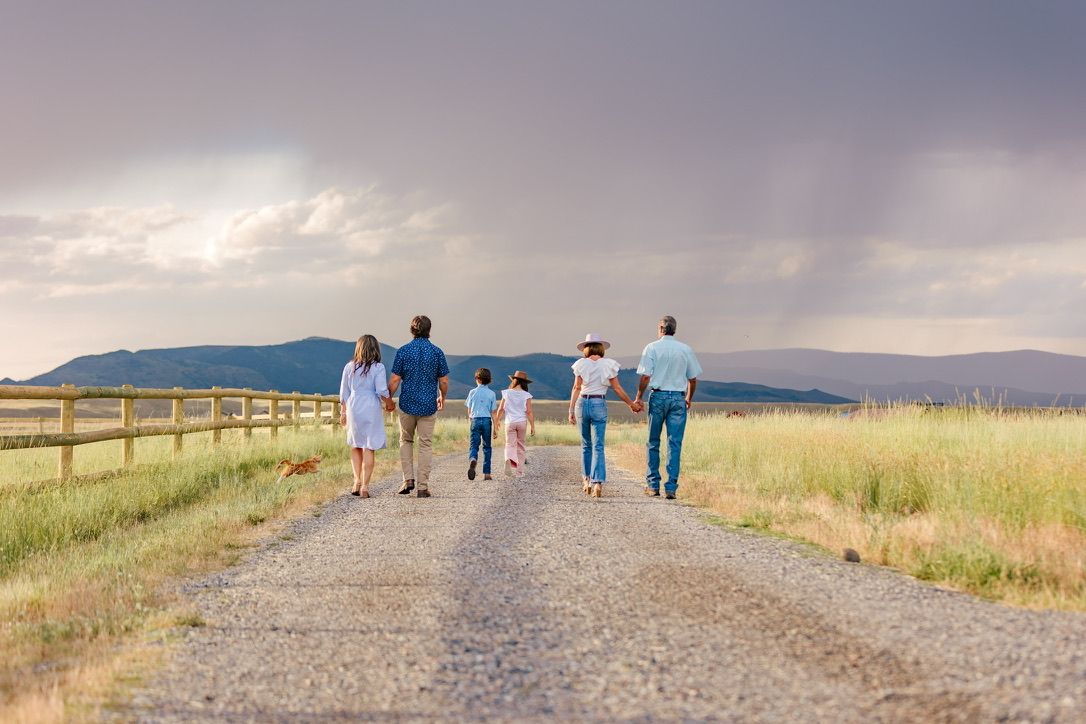 Group walking together on a dirt path through a scenic mountain landscape at sunset.