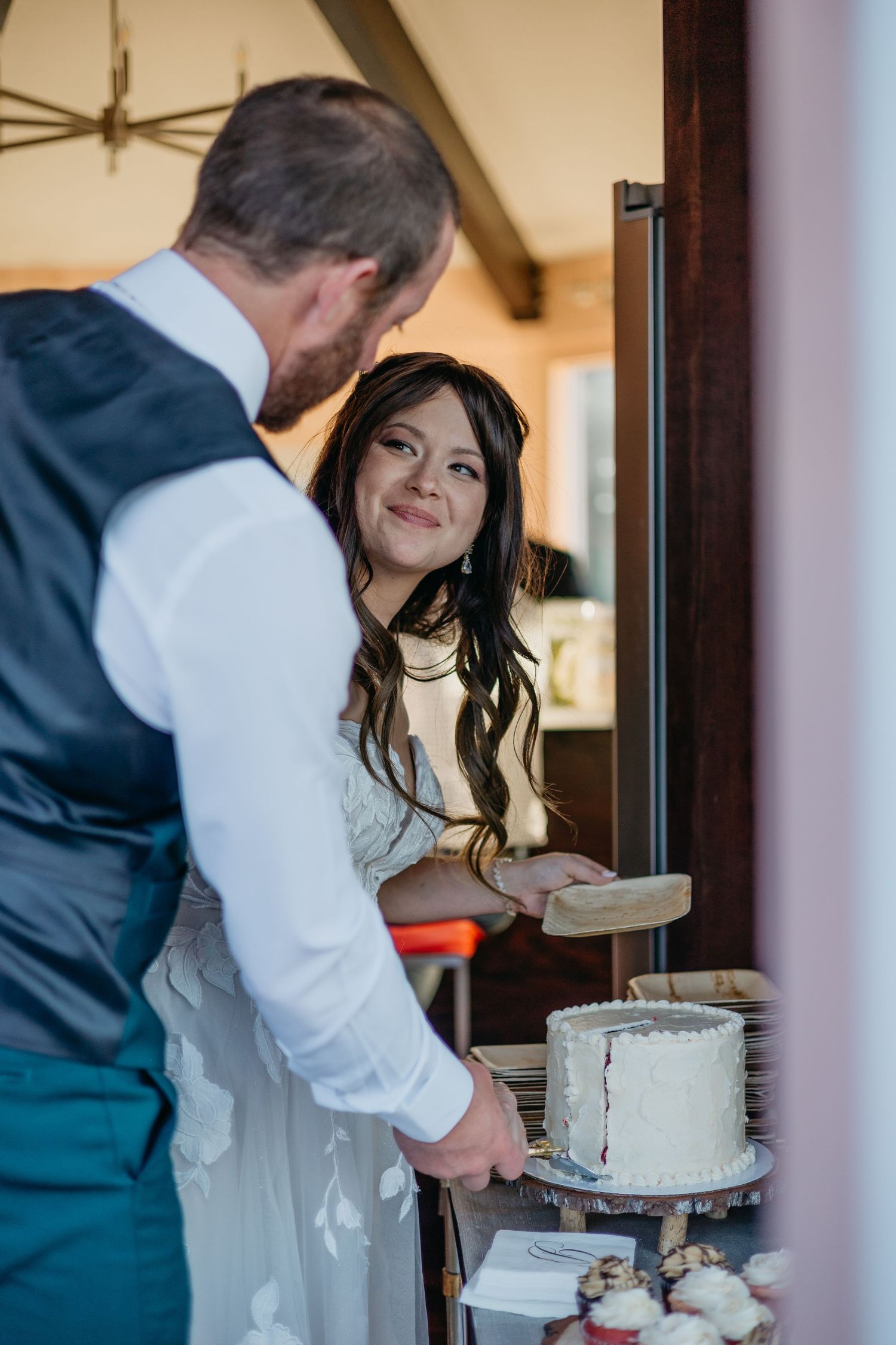 Couple cuts into their white wedding cake together at the reception.