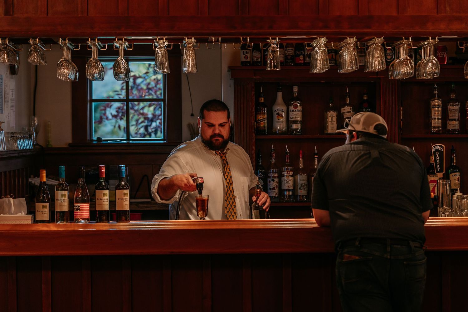 Rustic wooden bar setup with glass display shelves and ambient lighting.