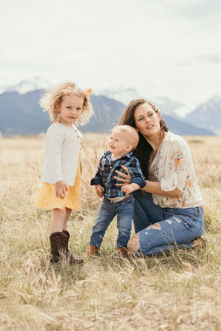 Children playing together in a golden wheat field with mountains in the background.