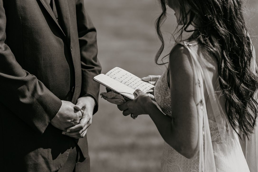Black and white photo of hands holding wedding vows during ceremony.