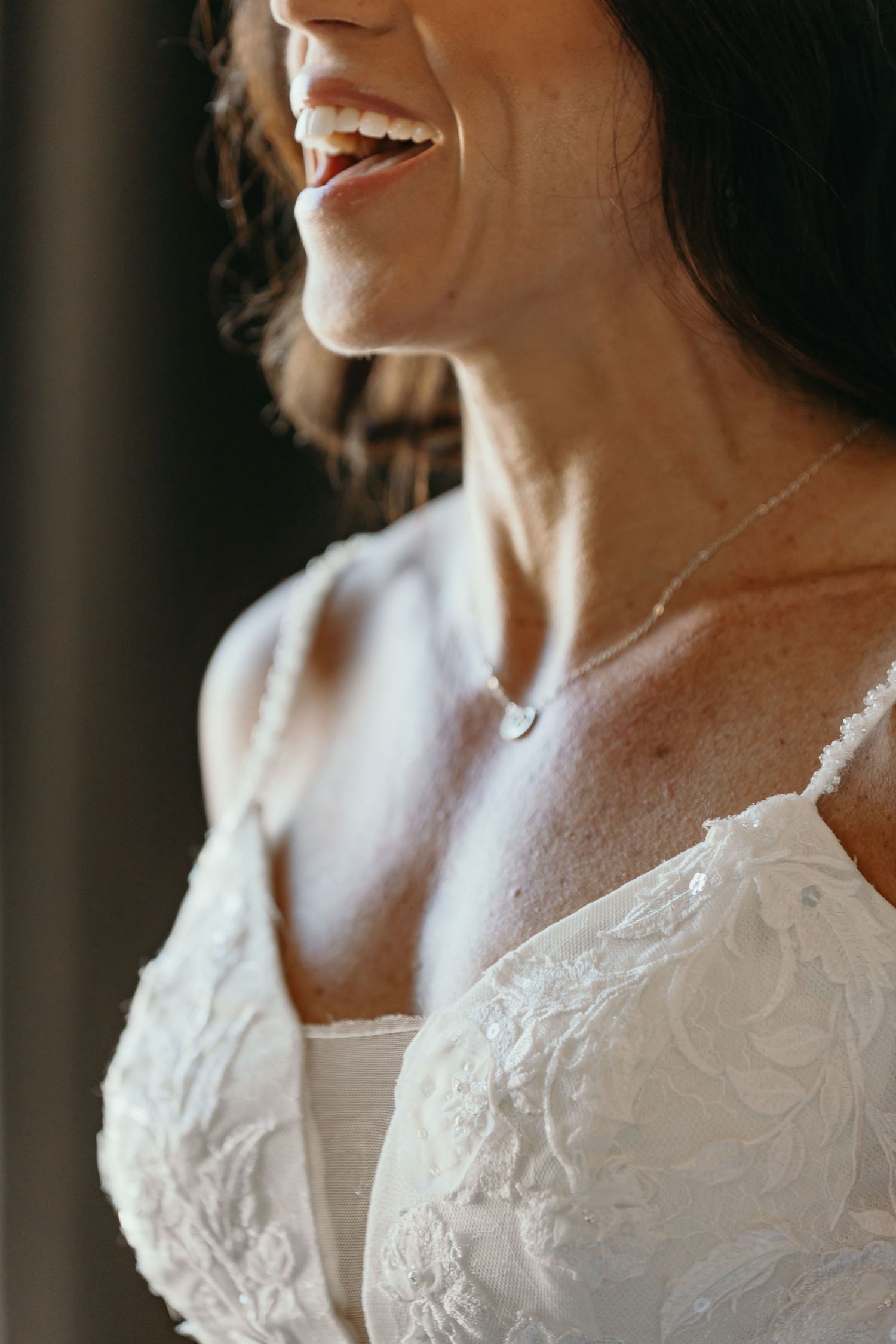Close-up details of intricate white lace wedding dress with floral embroidery patterns.