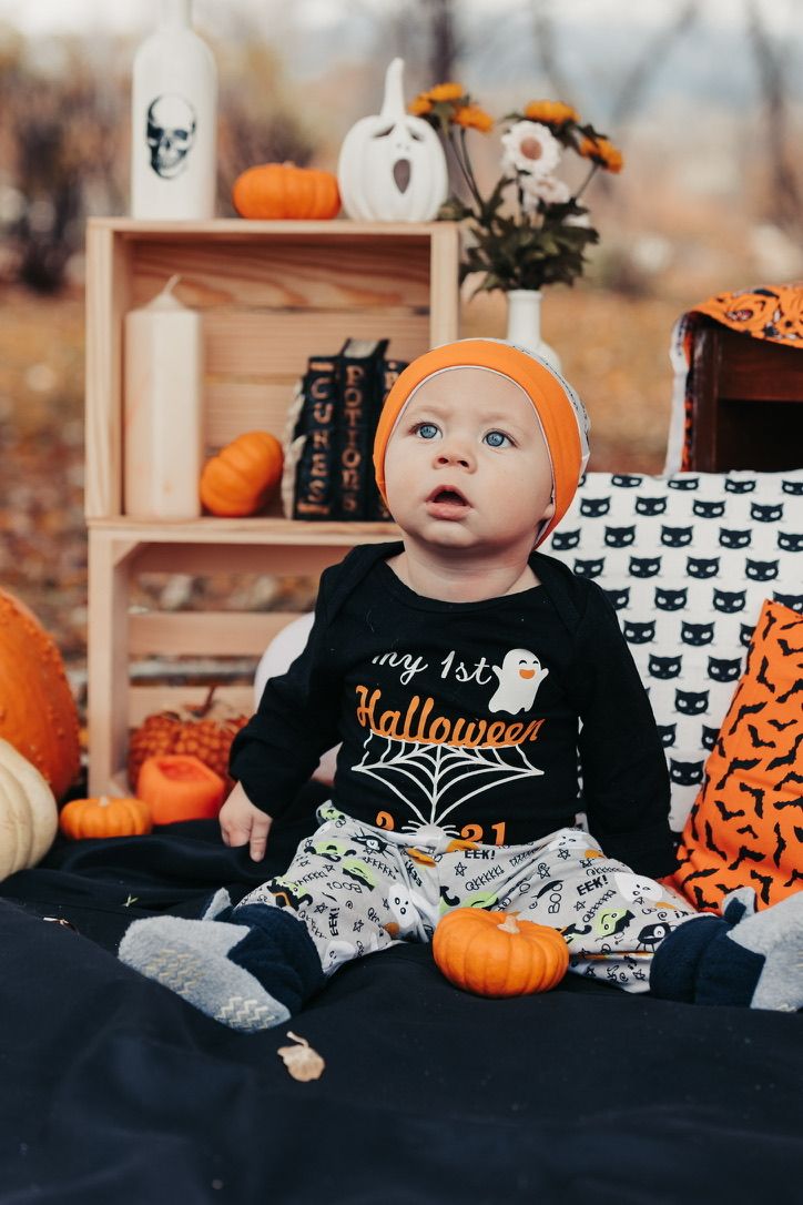 Halloween themed setting with pumpkins and spooky decorations on dark bedding.