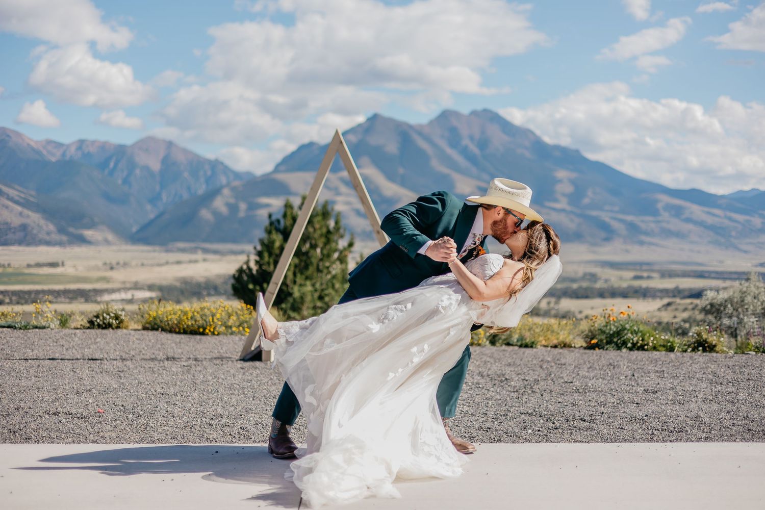 Wedding couple posing against majestic mountain backdrop with flowing dress.