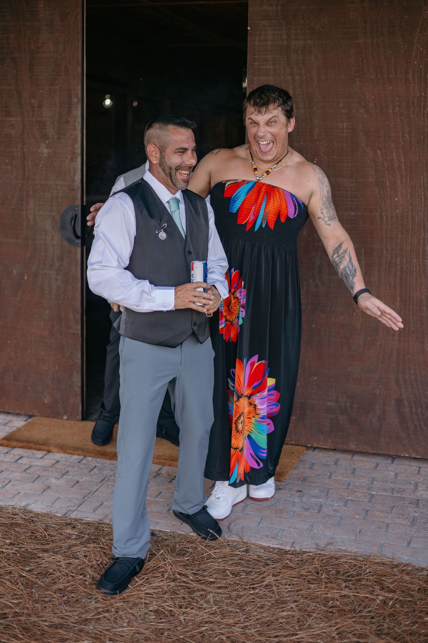 Two wedding guests share a laugh while one wears a colorful floral dress.