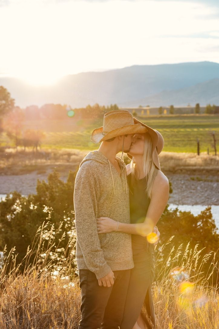 A romantic sunset moment in a field with mountains and golden light in the background.