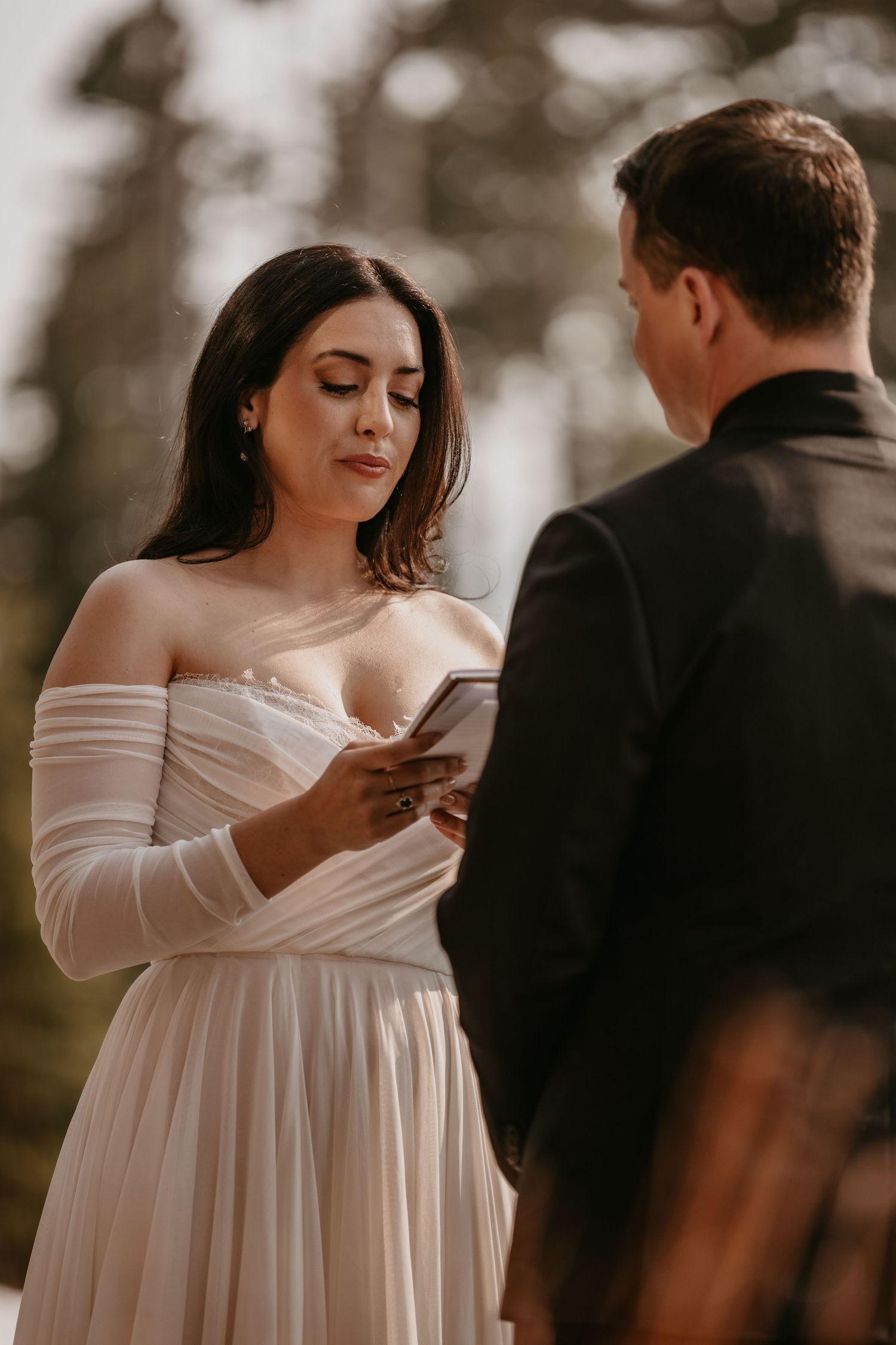 Intimate wedding portrait session with soft natural lighting among trees.
