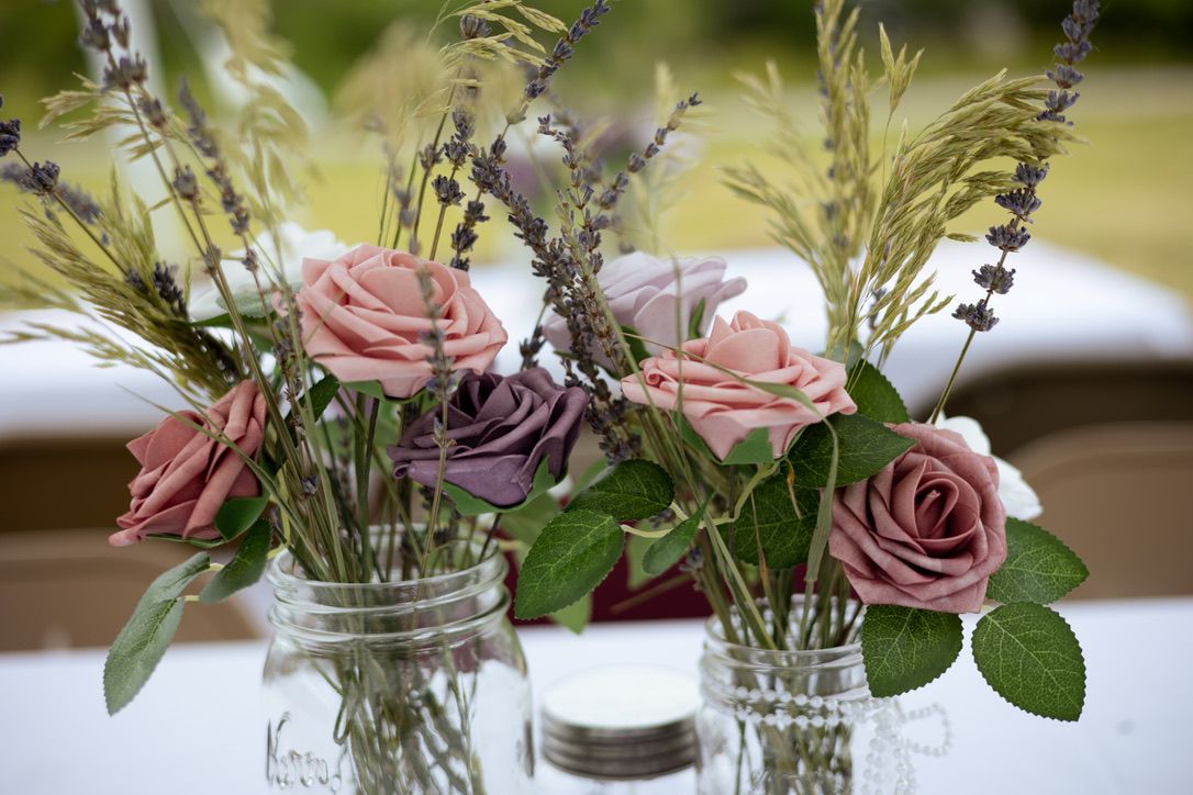 Row of delicate floral arrangements with pink roses and greenery in glass vases.