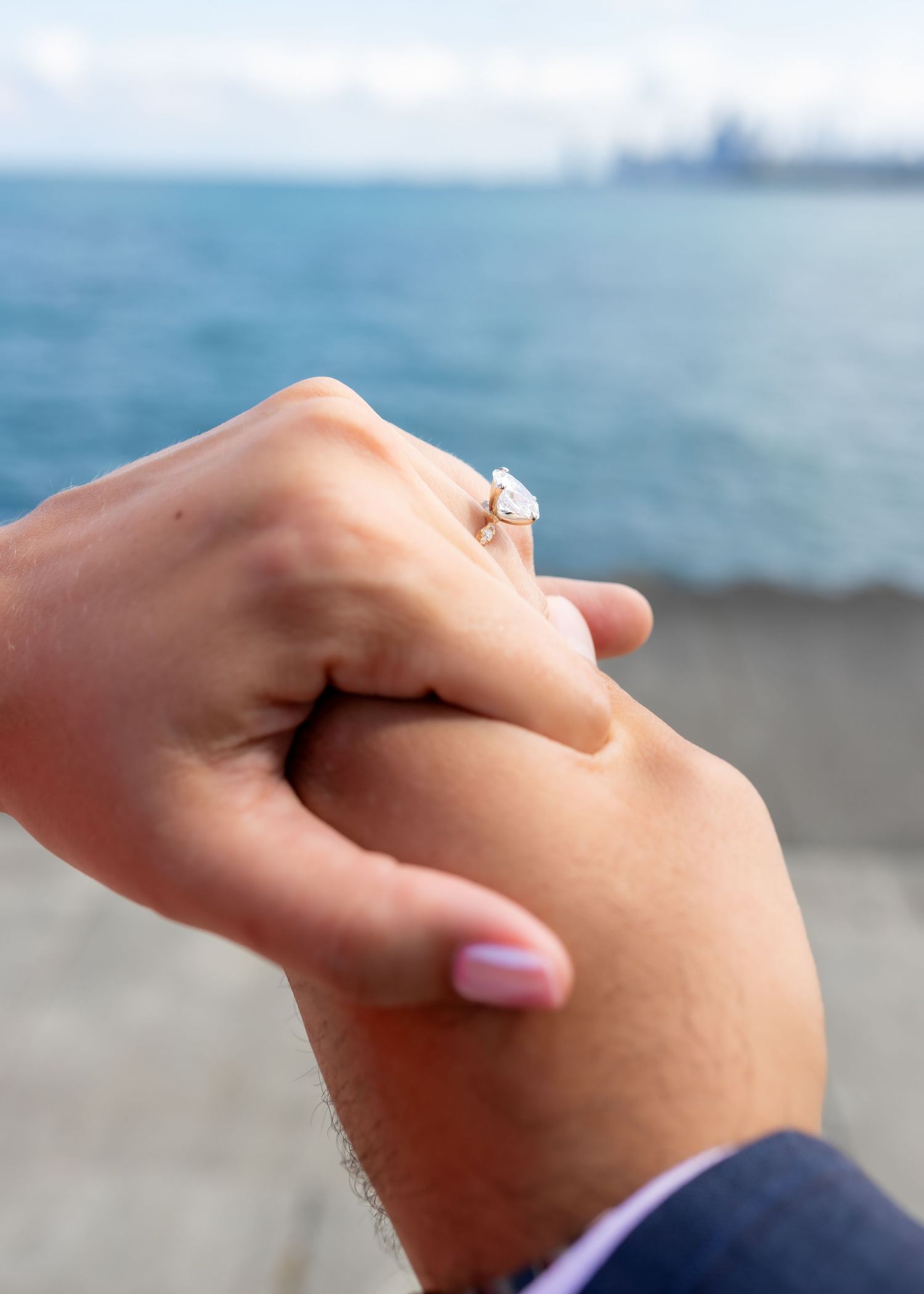 Close-up of an engagement ring sparkling against an ocean backdrop.