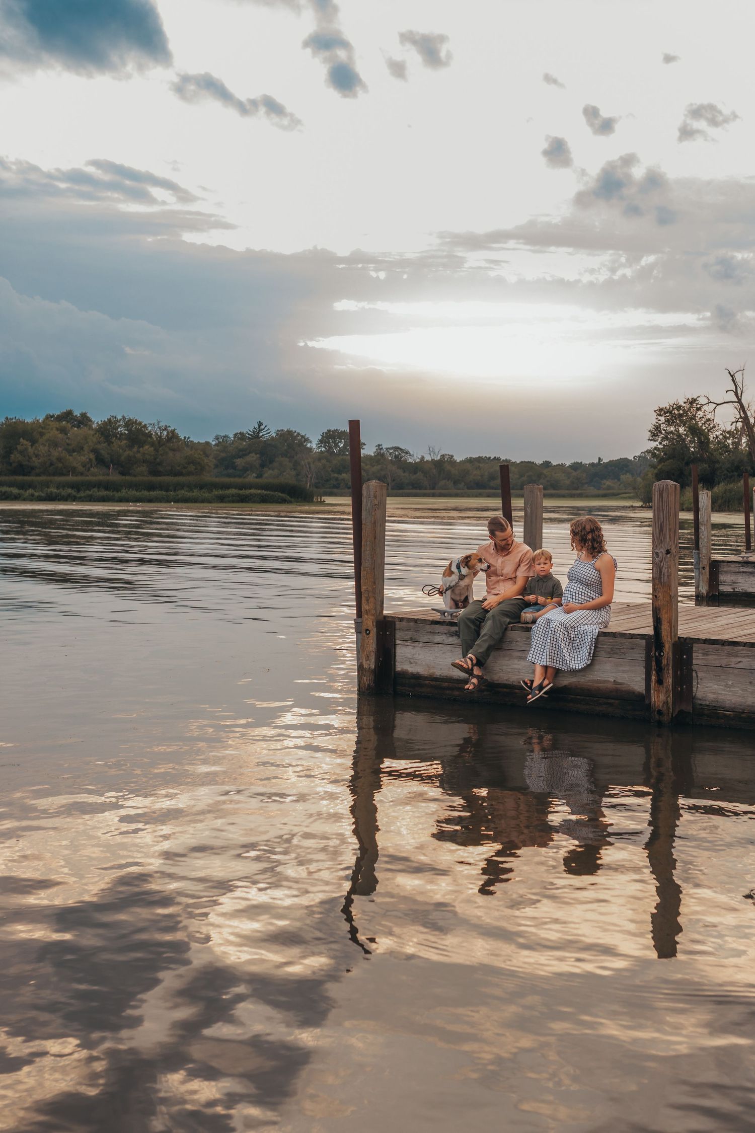 Family enjoying sunset together on a wooden dock over calm waters.