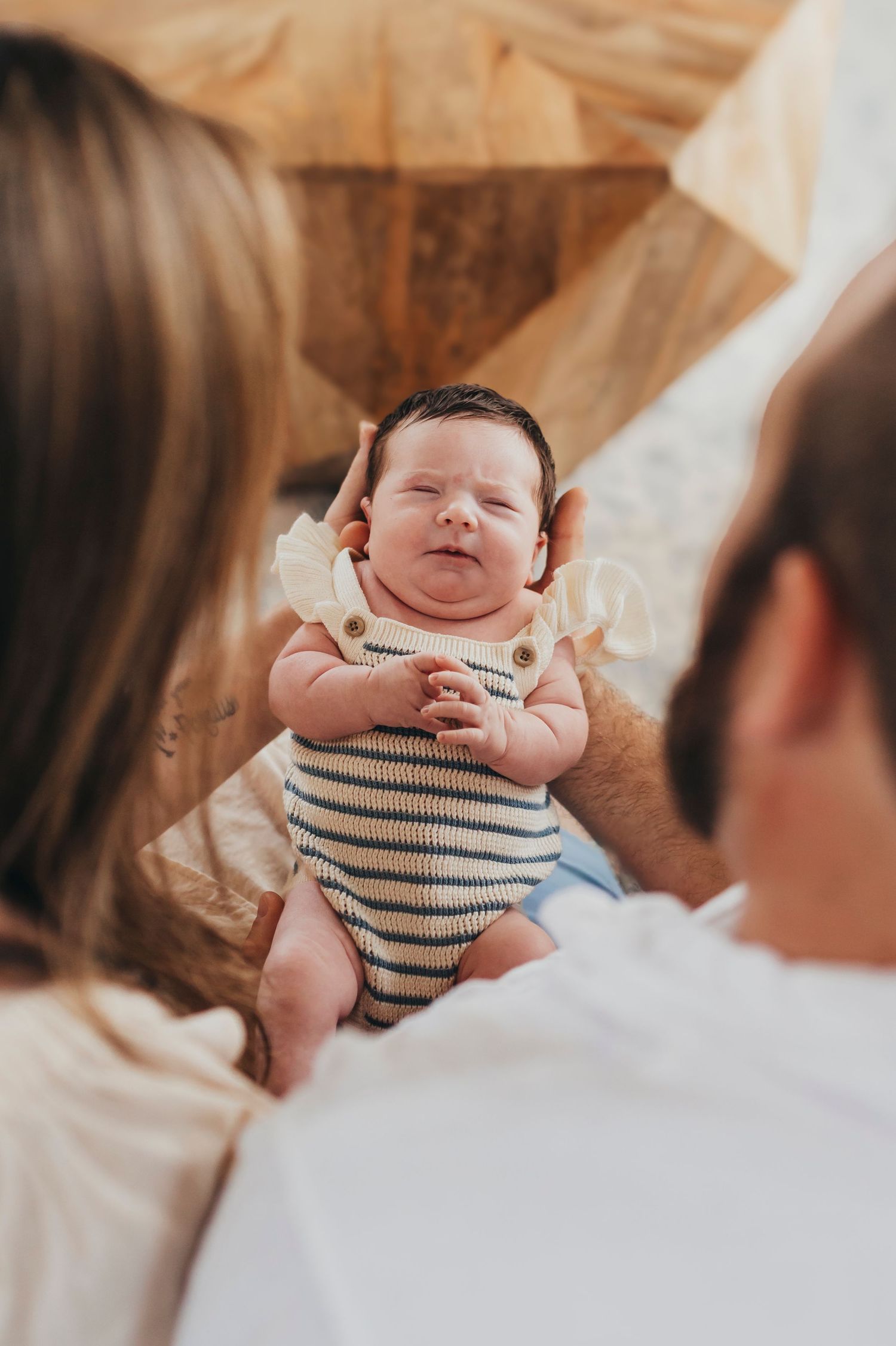 Newborn baby in striped onesie smiling during a lifestyle photo session.